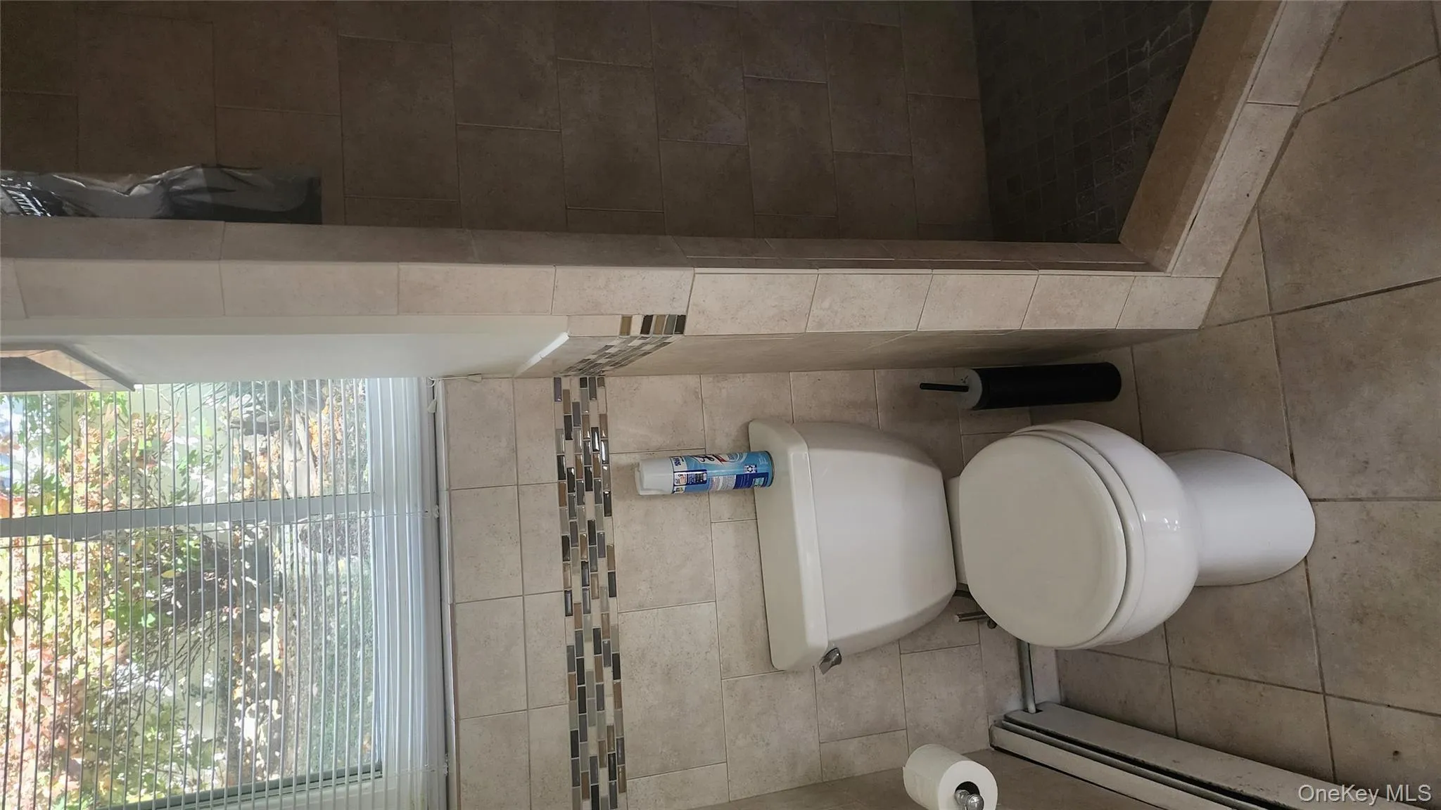 Full bathroom featuring a baseboard radiator, a stall shower, tile patterned floors, and tile walls Full bathroom featuring a baseboard radiator, a stall shower, tile patterned floors, and tile walls
