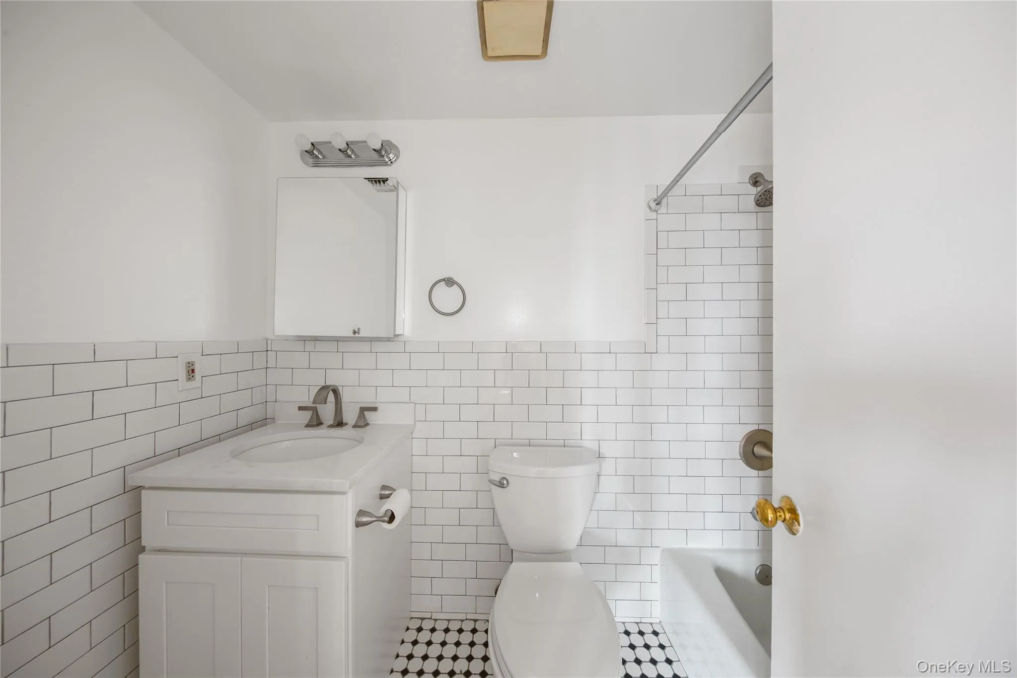 Full bath featuring bathing tub / shower combination, vanity, tile walls, and a wainscoted wall Full bath featuring bathing tub / shower combination, vanity, tile walls, and a wainscoted wall