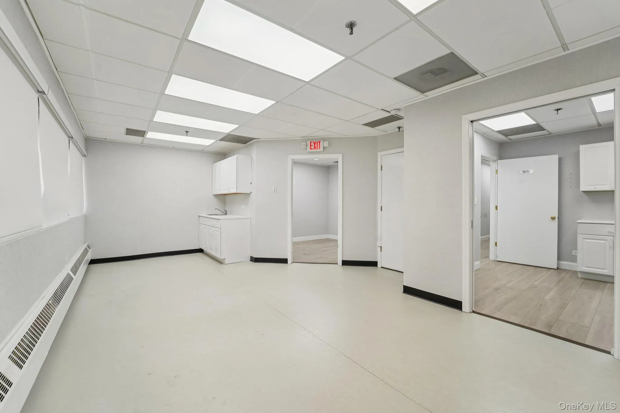 Below grade area featuring baseboard heating and a drop ceiling Below grade area featuring baseboard heating and a drop ceiling