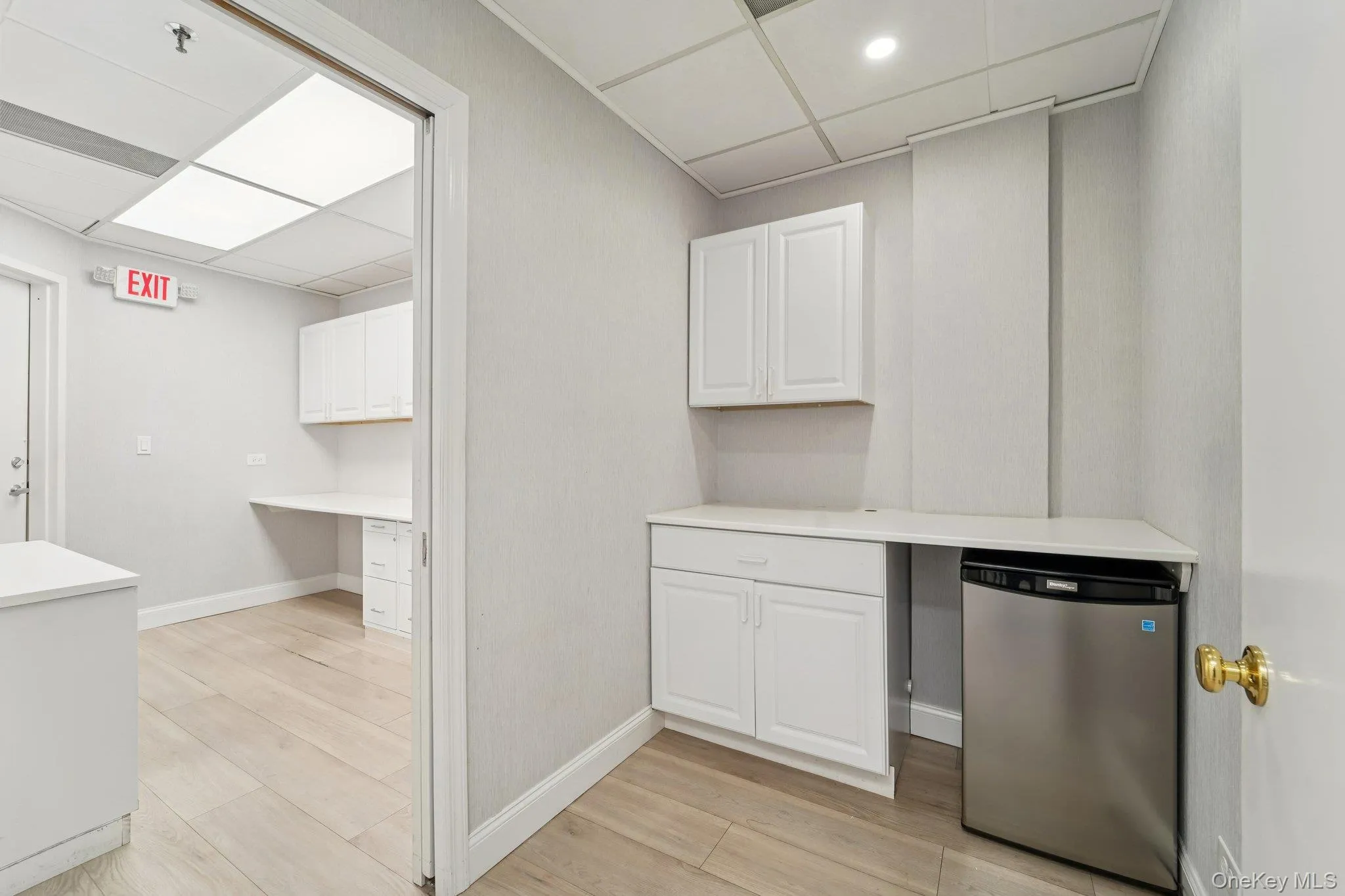 Kitchen with built in desk, light countertops, a drop ceiling, white cabinets, and stainless steel appliances Kitchen with built in desk, light countertops, a drop ceiling, white cabinets, and stainless steel appliances