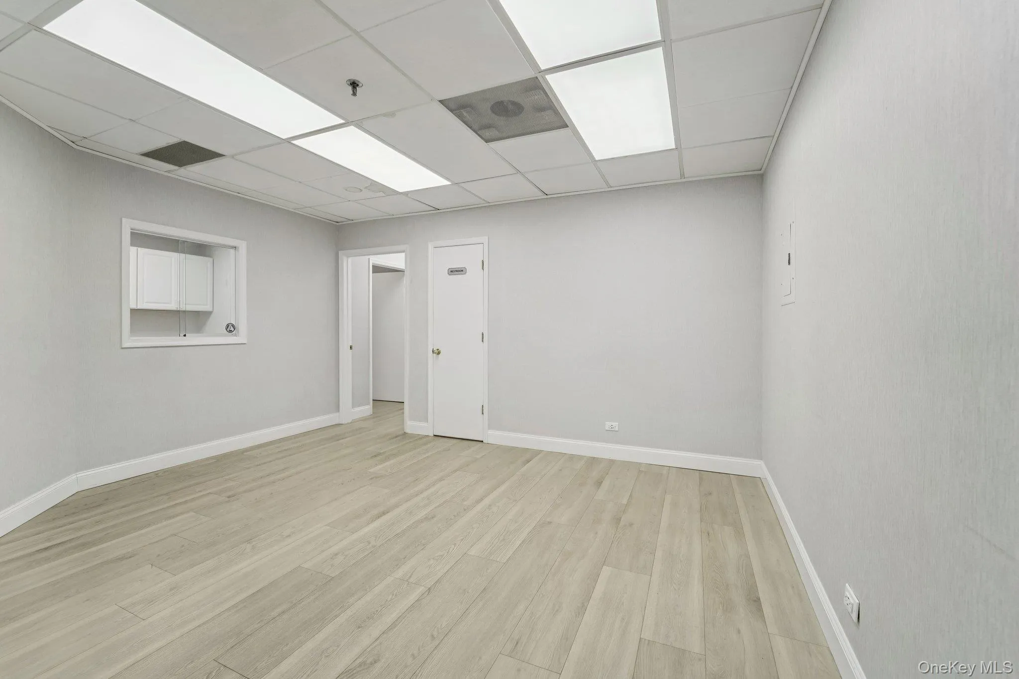 Empty room featuring a drop ceiling and light wood-style floors Empty room featuring a drop ceiling and light wood-style floors