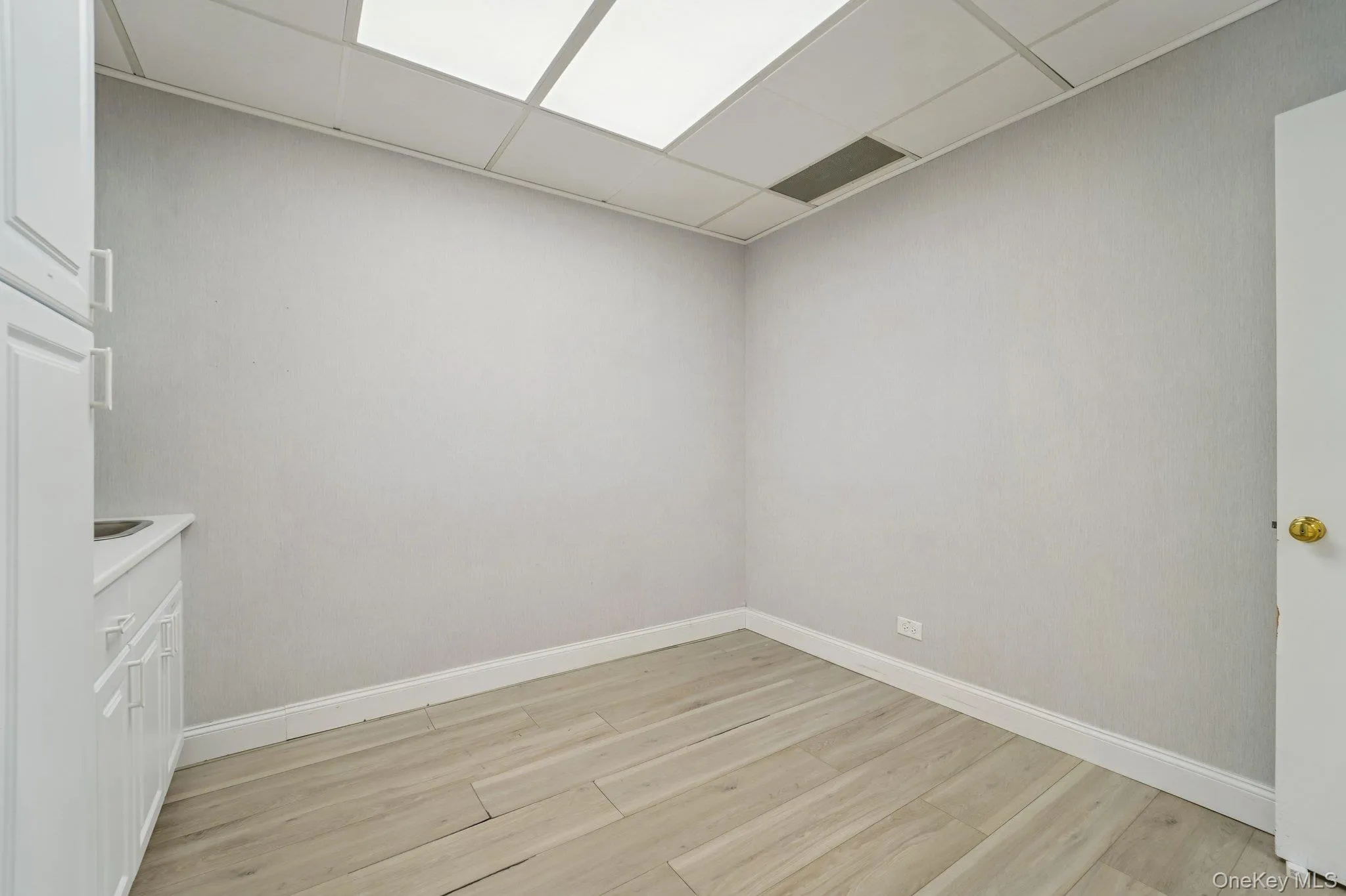 Unfurnished room featuring light wood-type flooring and a paneled ceiling Unfurnished room featuring light wood-type flooring and a paneled ceiling