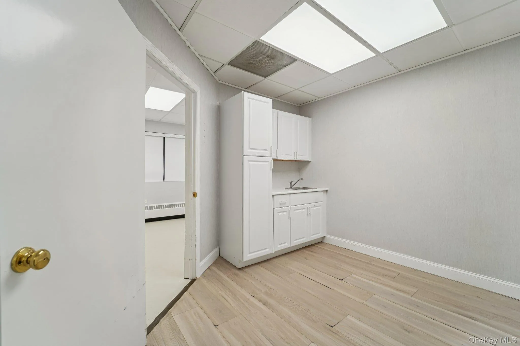 Laundry room featuring a drop ceiling, light wood-style flooring, and radiator heating unit Laundry room featuring a drop ceiling, light wood-style flooring, and radiator heating unit
