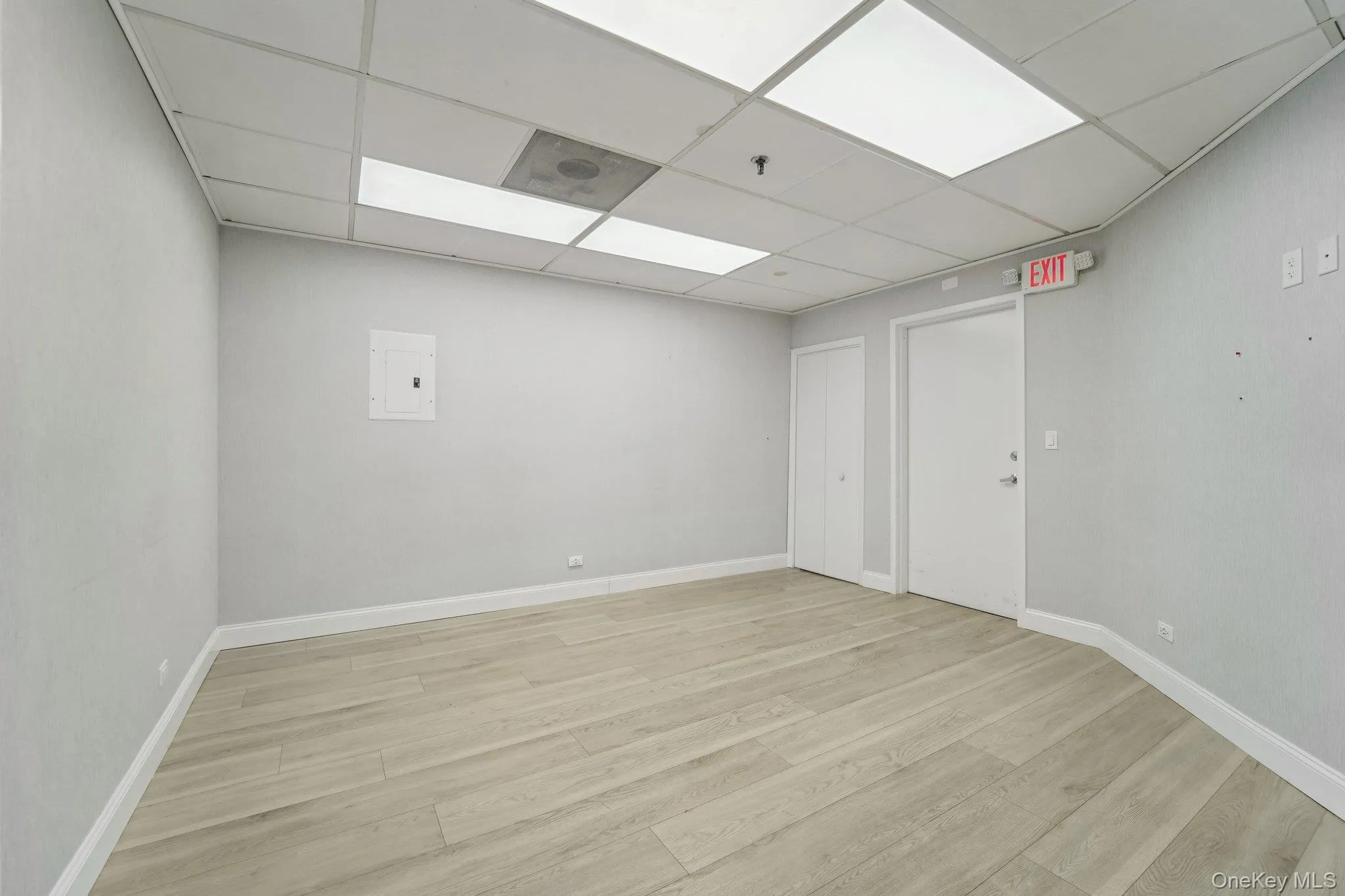 Unfurnished room with a drop ceiling and light wood-type flooring Unfurnished room with a drop ceiling and light wood-type flooring