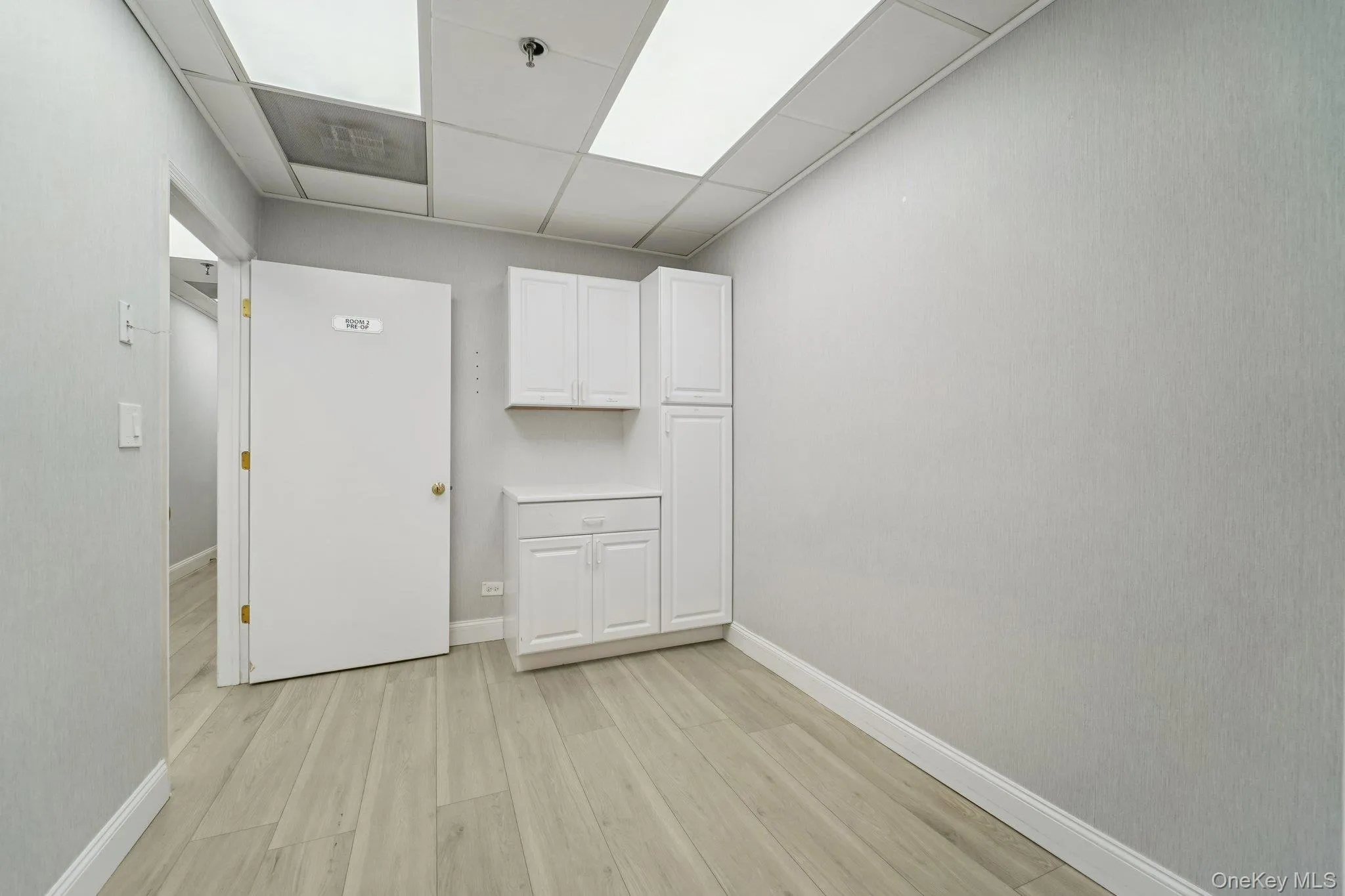 Unfurnished room with light wood-type flooring and a drop ceiling Unfurnished room with light wood-type flooring and a drop ceiling