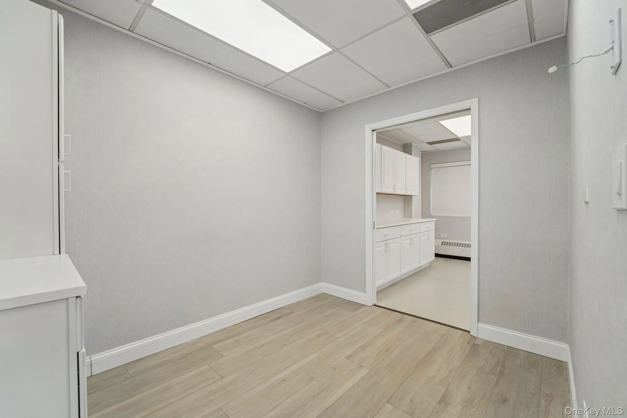 Empty room with a drop ceiling and light wood finished floors Empty room with a drop ceiling and light wood finished floors