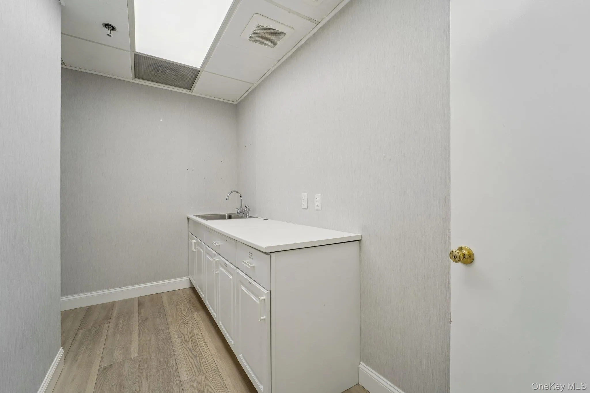 Laundry area with light wood finished floors and a paneled ceiling Laundry area with light wood finished floors and a paneled ceiling