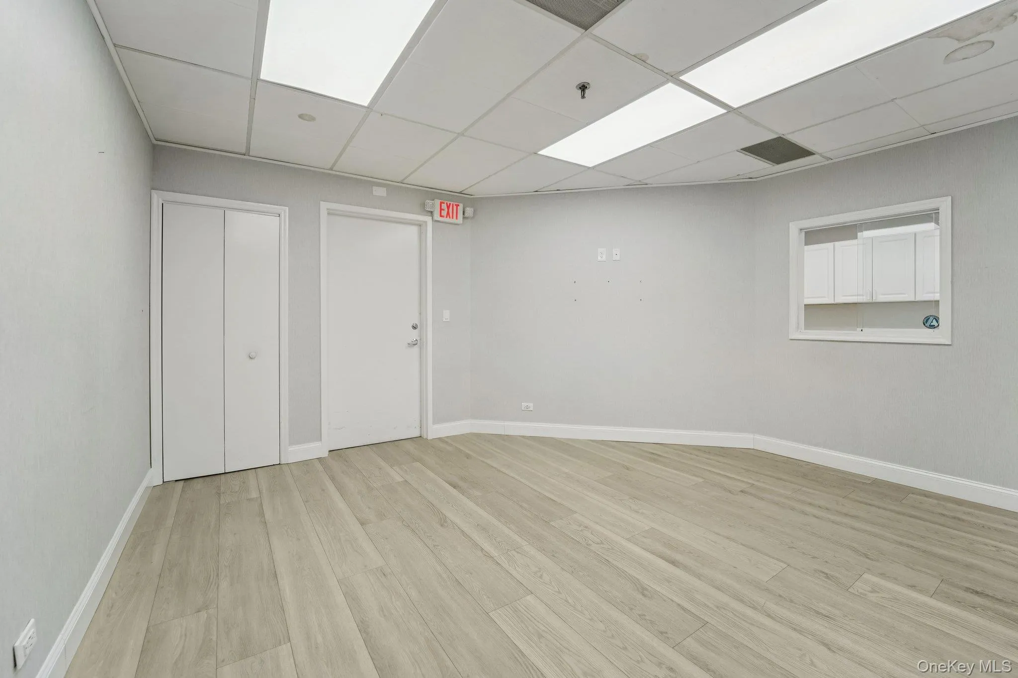 Empty room featuring light wood finished floors and a drop ceiling Empty room featuring light wood finished floors and a drop ceiling