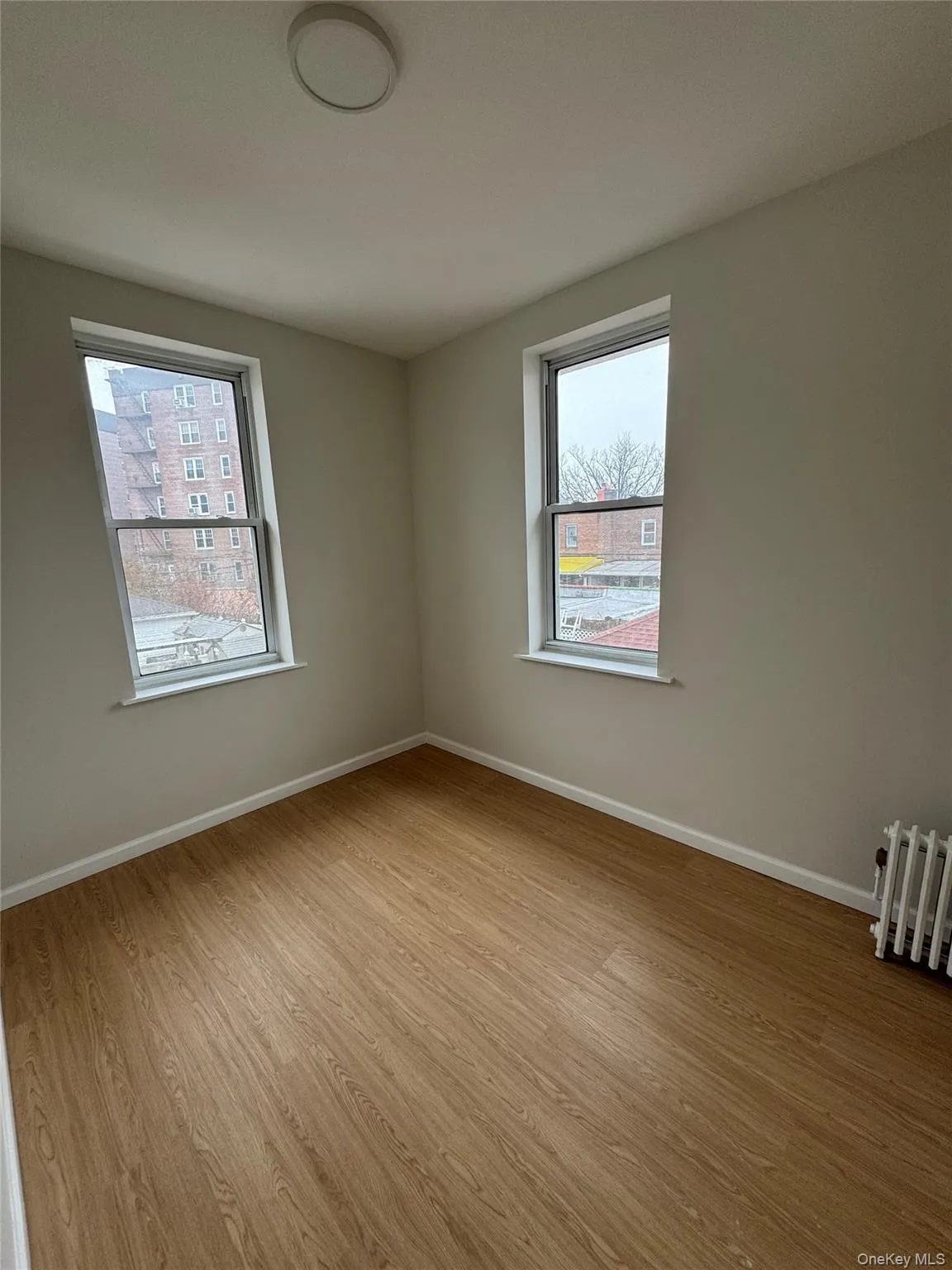 Bedroom featuring light wood-style flooring and radiator heating unit Bedroom featuring light wood-style flooring and radiator heating unit
