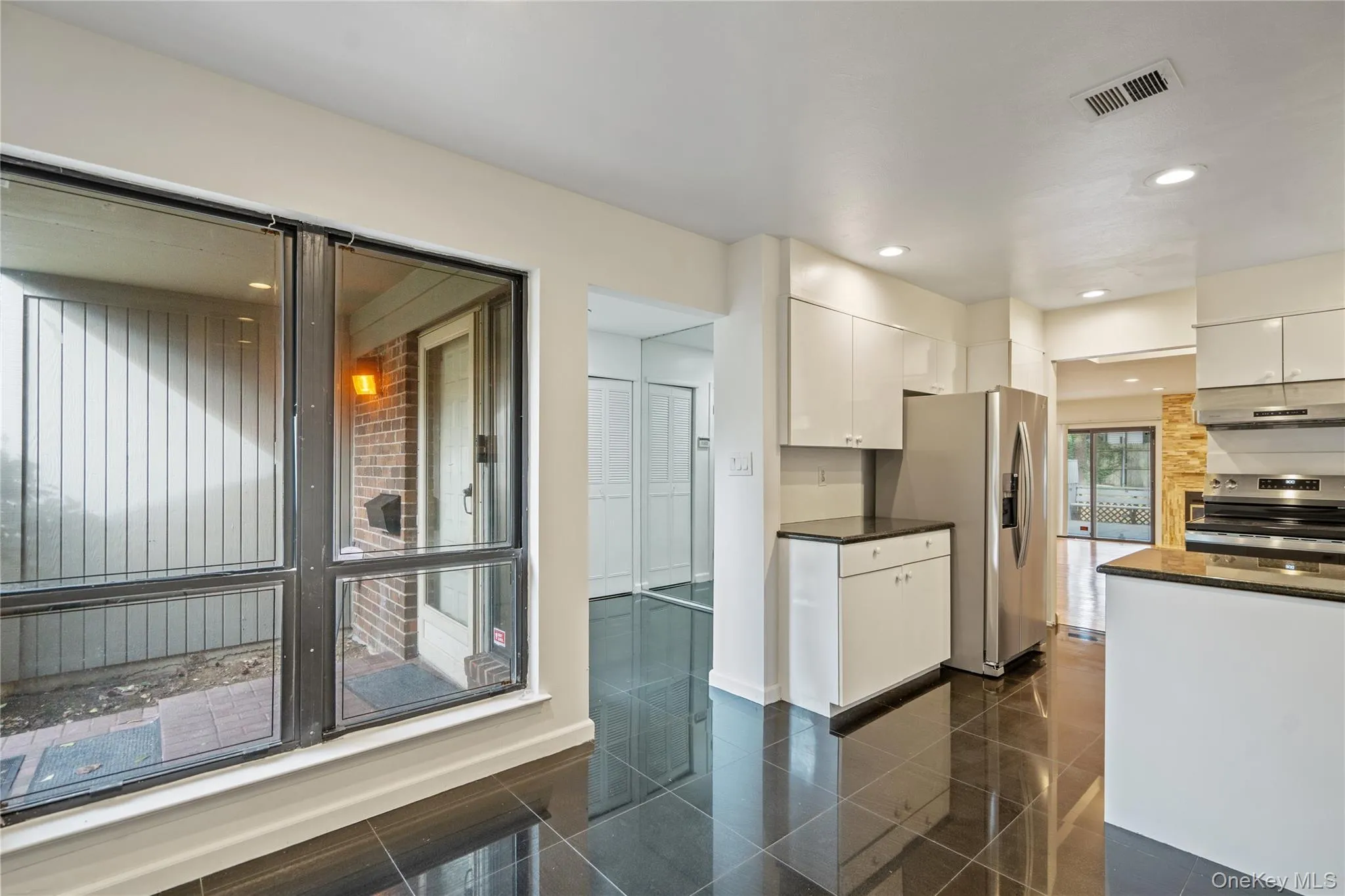 Kitchen with white cabinetry, stainless steel appliances, under cabinet range hood, recessed lighting, and dark stone countertops Kitchen with white cabinetry, stainless steel appliances, under cabinet range hood, recessed lighting, and dark stone countertops
