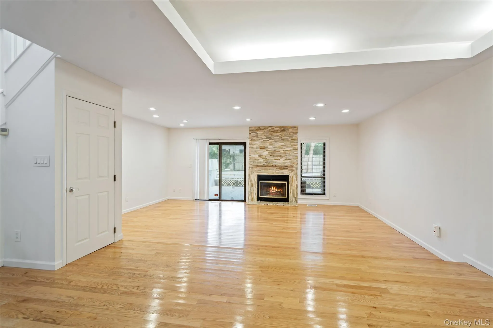 Unfurnished living room featuring light wood-style flooring, a fireplace, and recessed lighting Unfurnished living room featuring light wood-style flooring, a fireplace, and recessed lighting