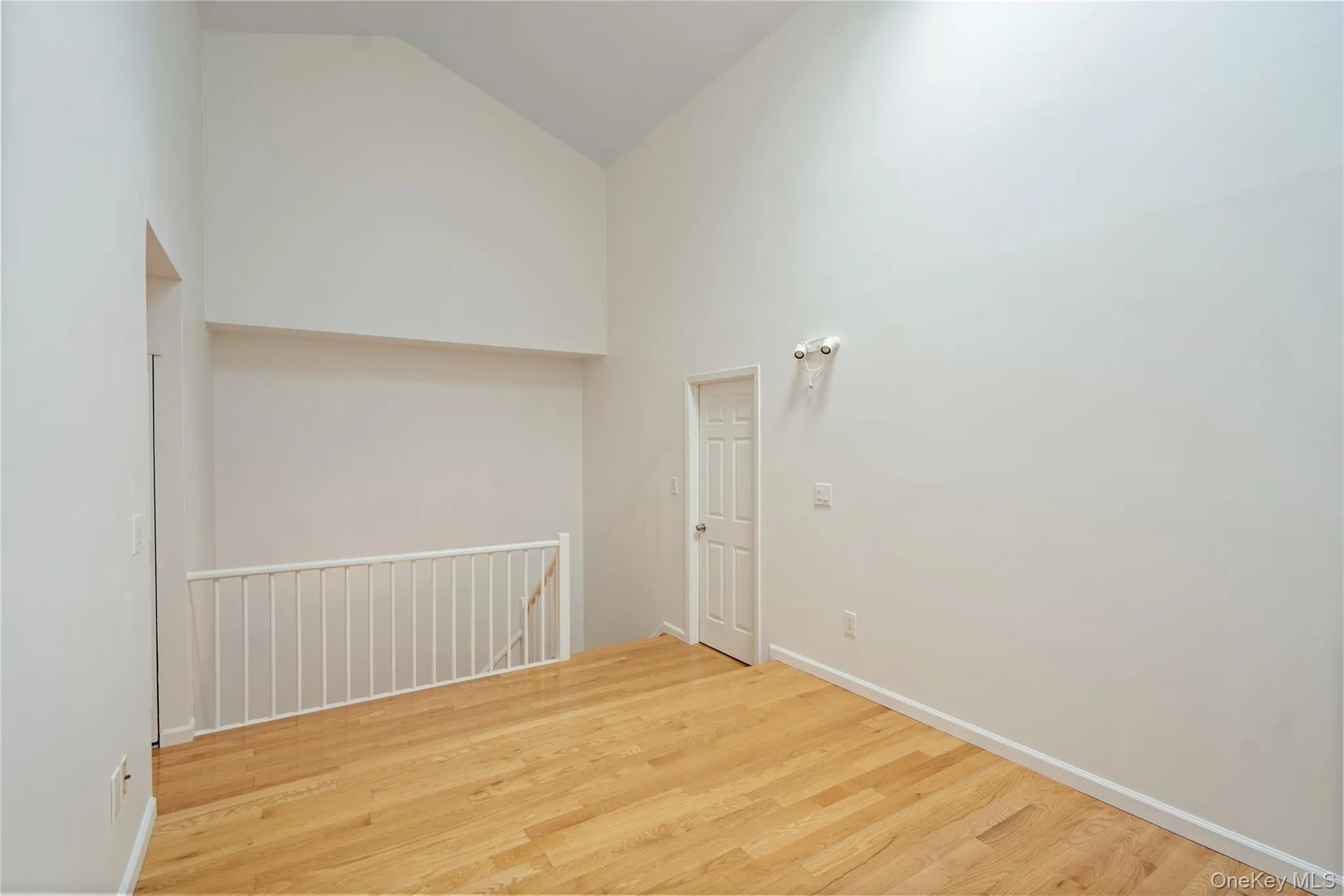 Unfurnished room featuring high vaulted ceiling and wood finished floors Unfurnished room featuring high vaulted ceiling and wood finished floors