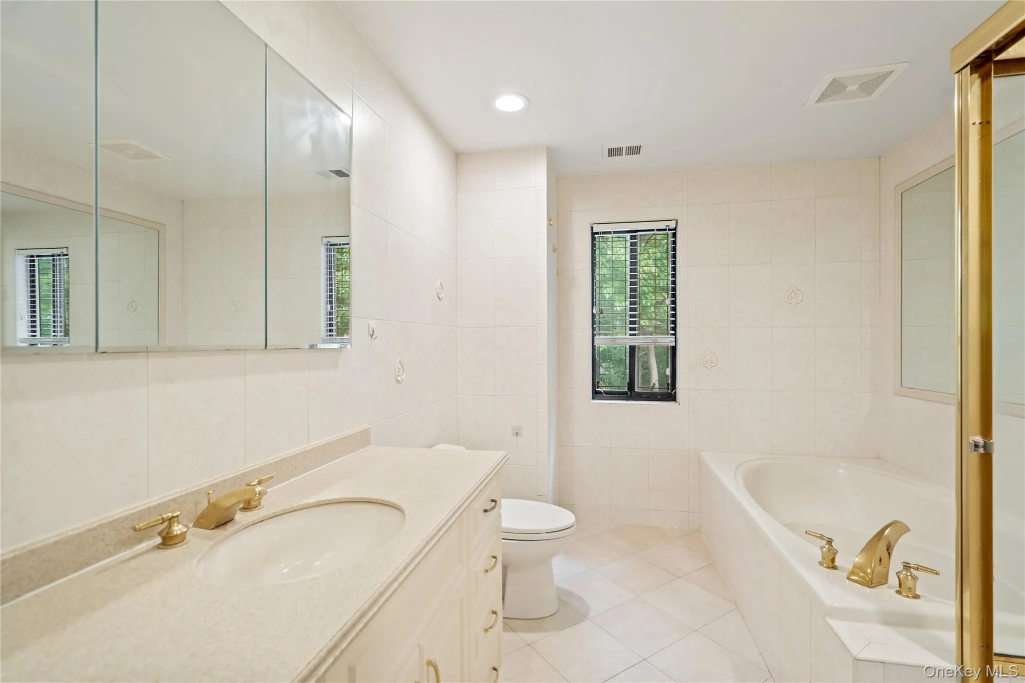 Full bathroom with a bath, tile walls, vanity, light tile patterned floors, and recessed lighting Full bathroom with a bath, tile walls, vanity, light tile patterned floors, and recessed lighting