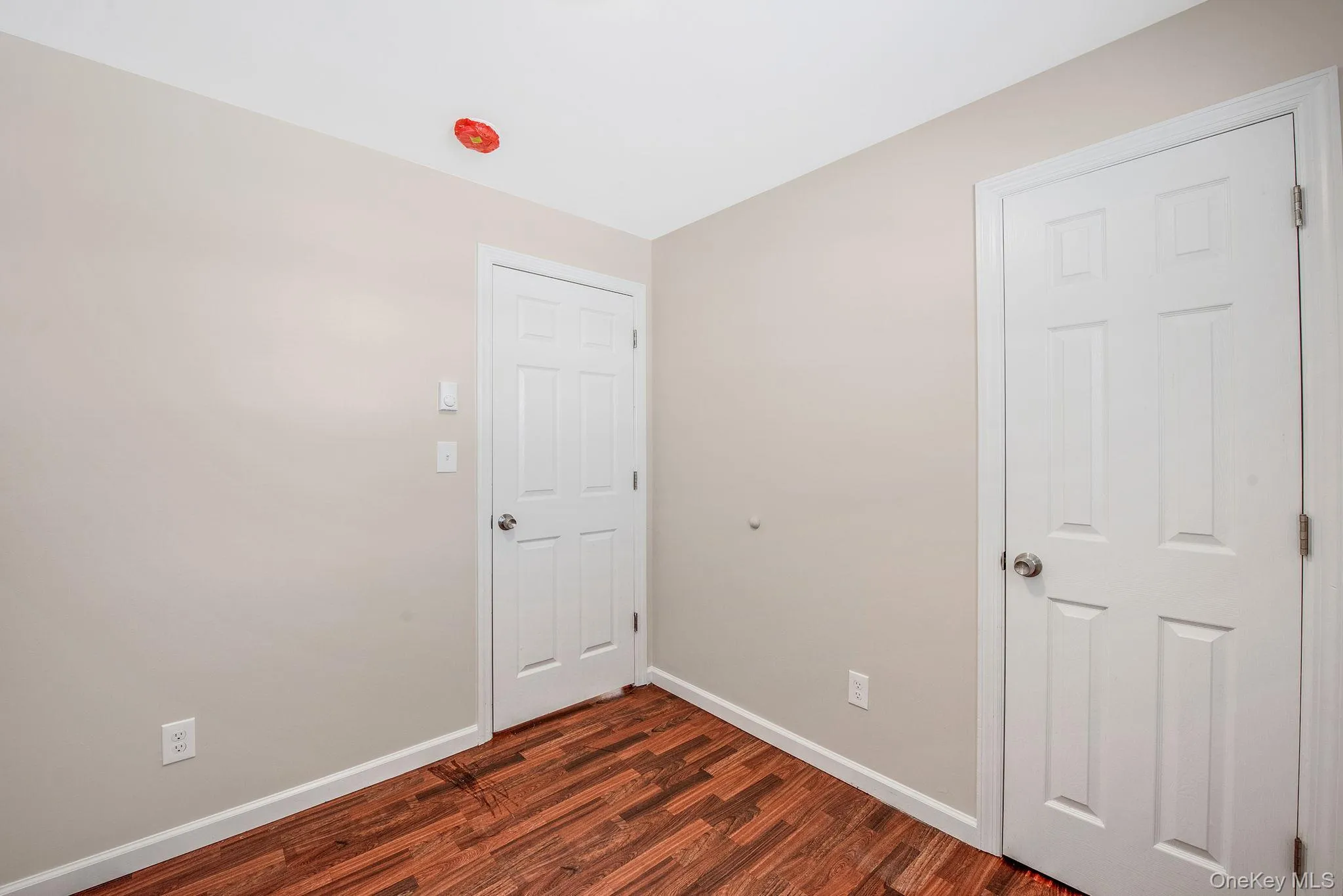 Unfurnished bedroom with baseboards and dark wood-style floors Unfurnished bedroom with baseboards and dark wood-style floors