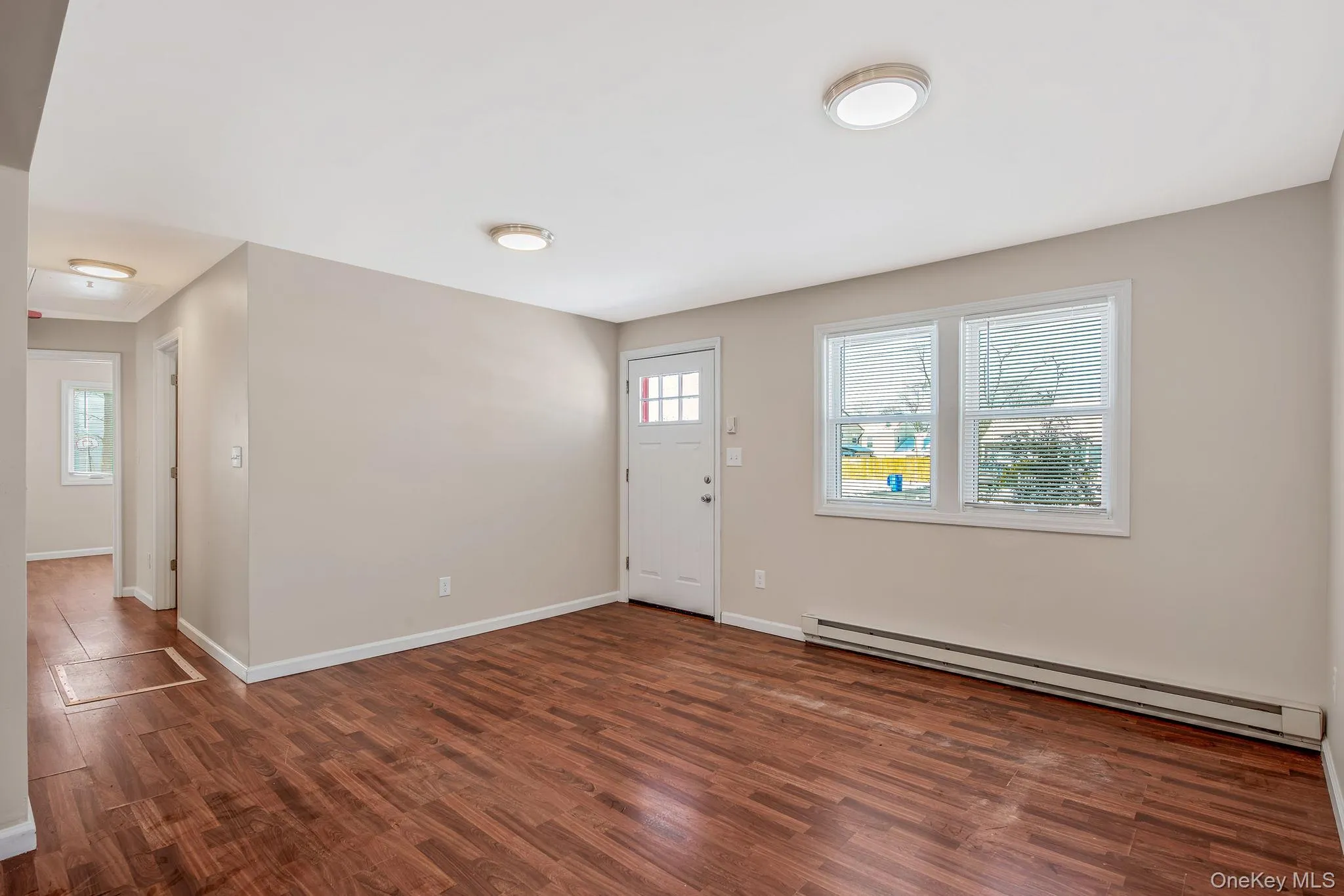 Entrance foyer with a baseboard radiator, dark wood-style flooring, and healthy amount of natural light Entrance foyer with a baseboard radiator, dark wood-style flooring, and healthy amount of natural light