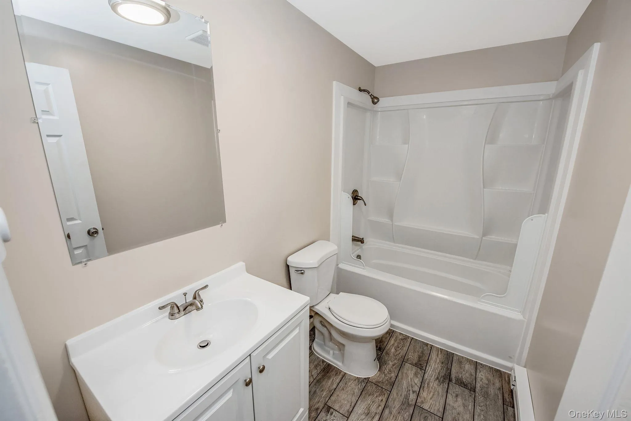 Bathroom with vanity, wood finish floors, and shower / washtub combination Bathroom with vanity, wood finish floors, and shower / washtub combination