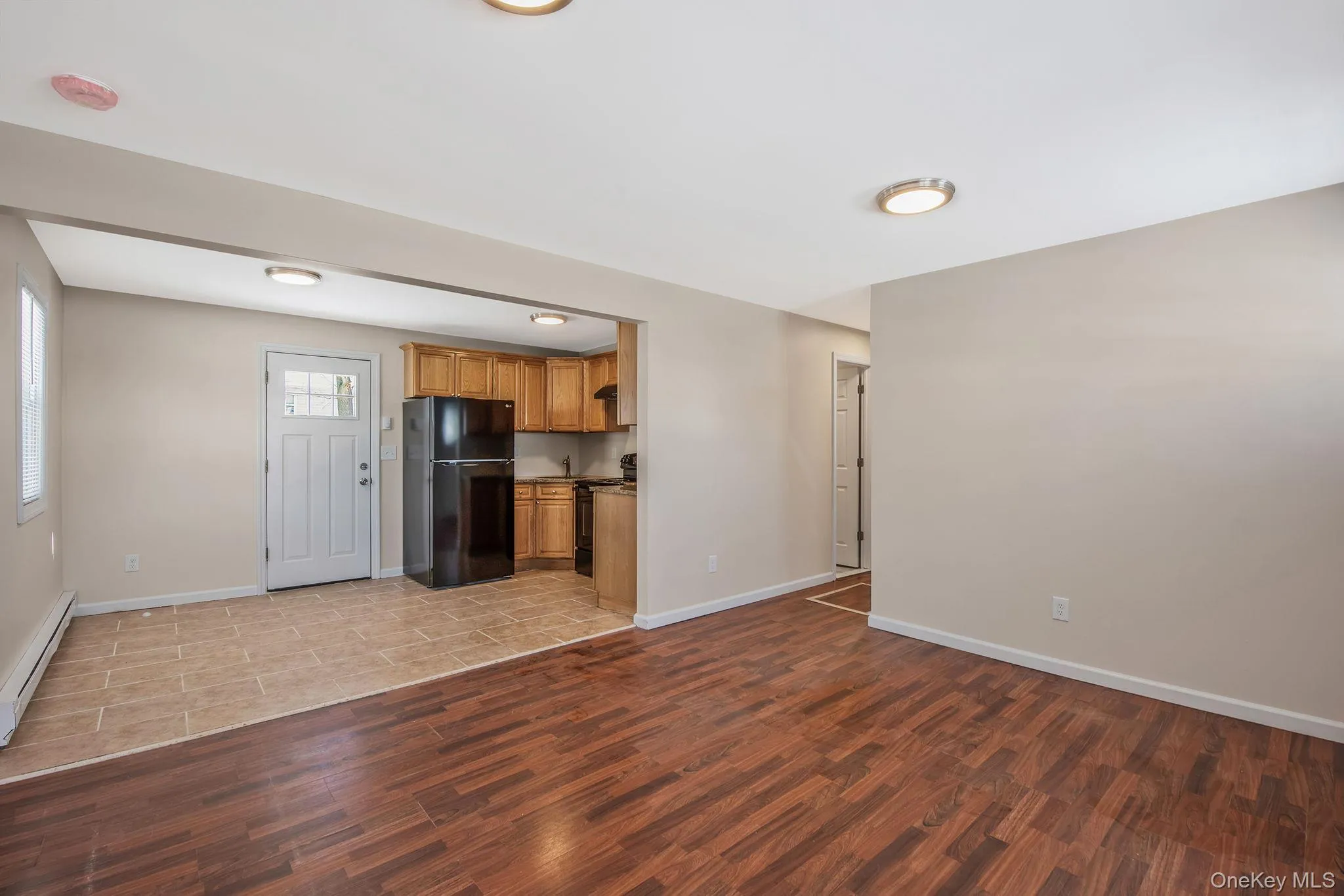 Unfurnished living room with wood finish floors and a baseboard heating unit Unfurnished living room with wood finish floors and a baseboard heating unit