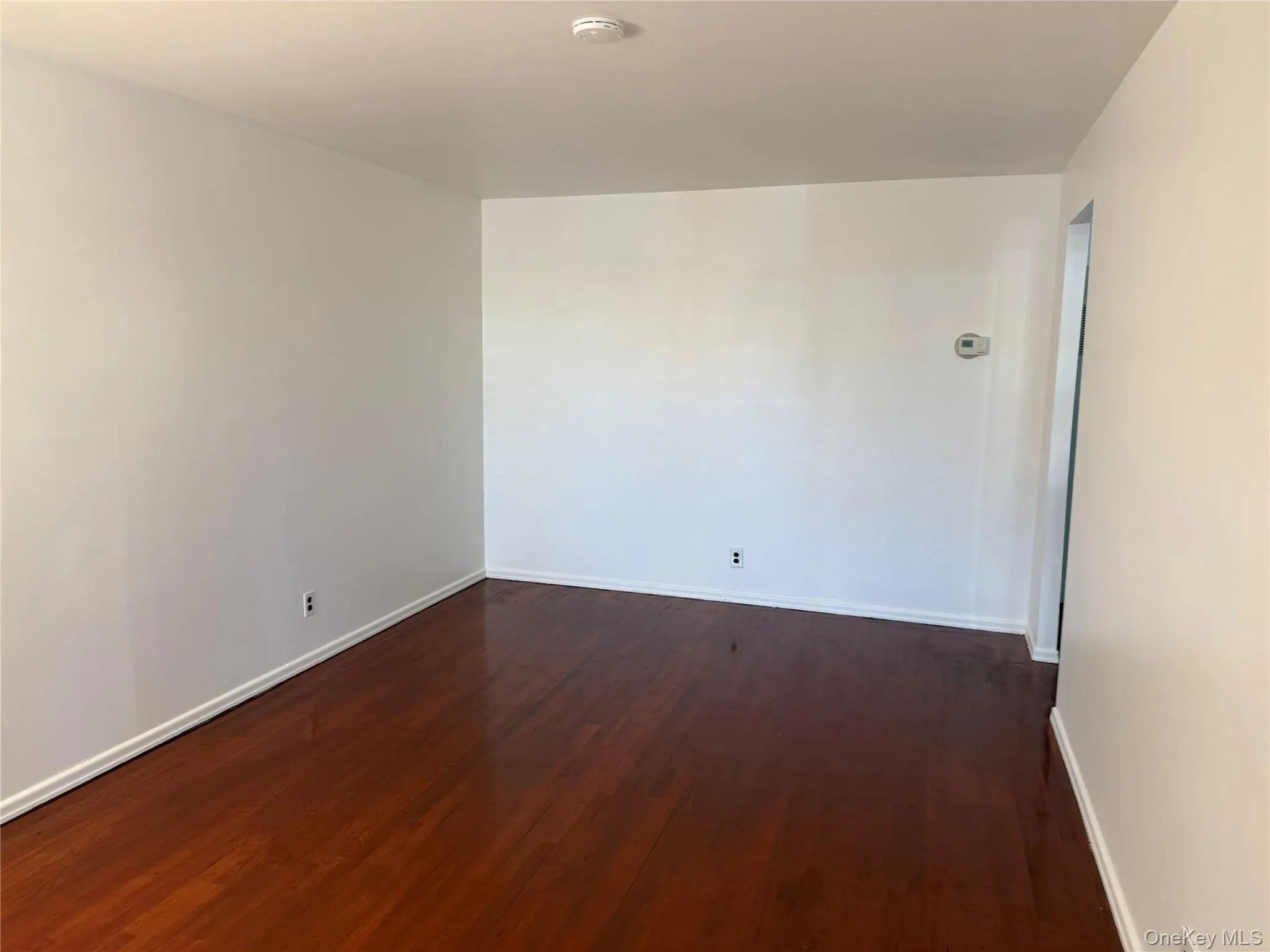 Spare room featuring dark wood-style flooring and baseboards Spare room featuring dark wood-style flooring and baseboards
