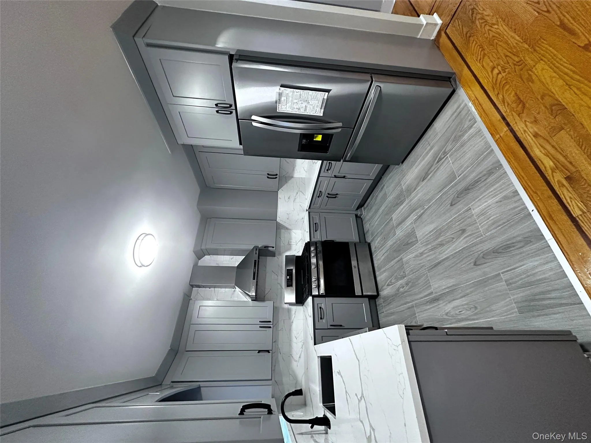 Kitchen featuring gray cabinetry, refrigerator, stainless steel range oven, backsplash, and exhaust hood Kitchen featuring gray cabinetry, refrigerator, stainless steel range oven, backsplash, and exhaust hood