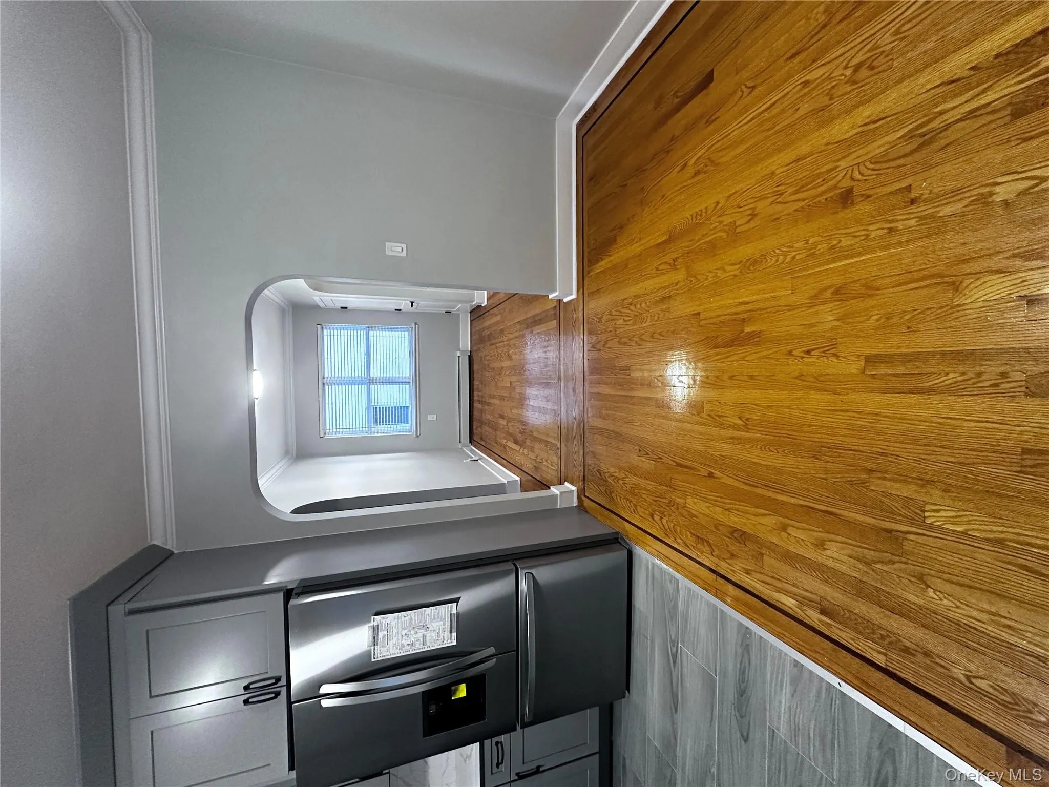 Corridor with light wood-style floors, ornamental molding, arched walkways, and a baseboard heating unit Corridor with light wood-style floors, ornamental molding, arched walkways, and a baseboard heating unit