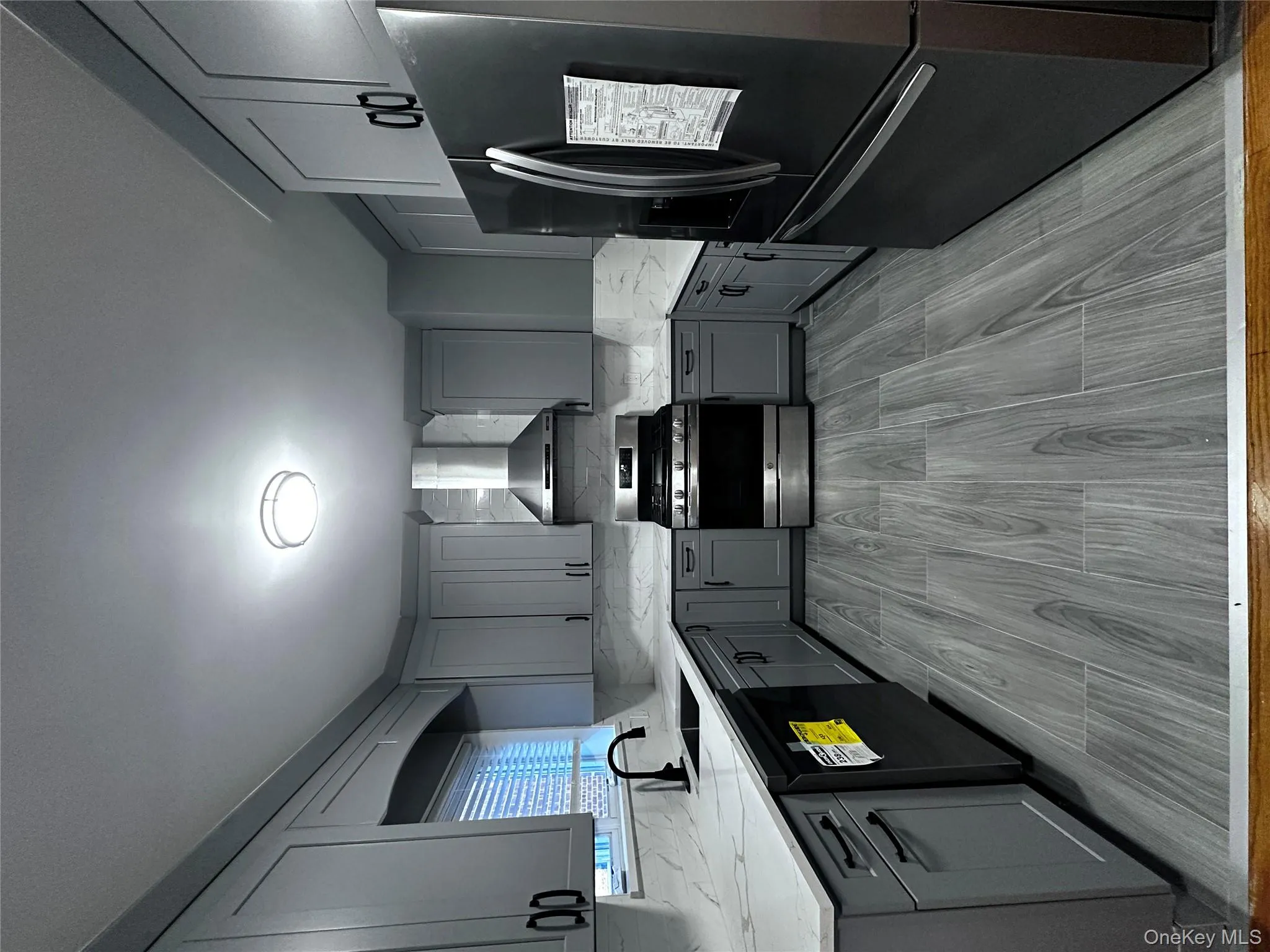 Kitchen featuring fridge, gray cabinetry, gas stove, and decorative backsplash Kitchen featuring fridge, gray cabinetry, gas stove, and decorative backsplash