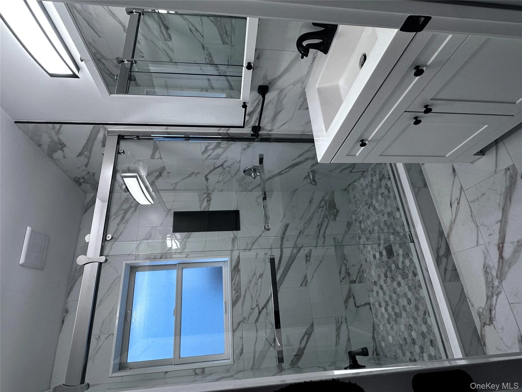 Bathroom with light marble finish flooring, vanity, plenty of natural light, and a marble finish shower Bathroom with light marble finish flooring, vanity, plenty of natural light, and a marble finish shower