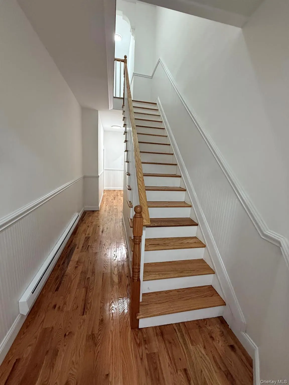 Stairway with a baseboard heating unit and wood finished floors Stairway with a baseboard heating unit and wood finished floors