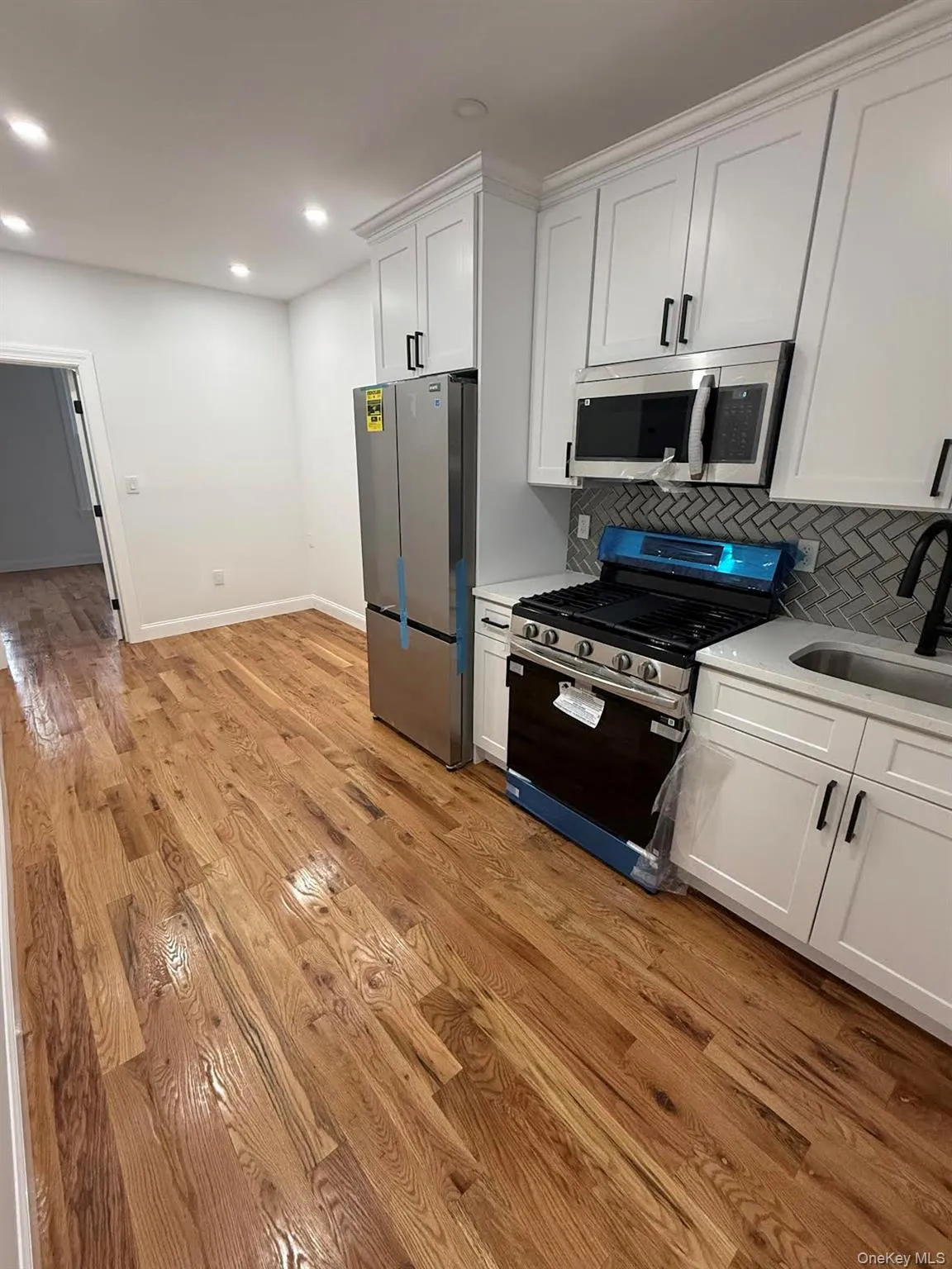 Kitchen featuring appliances with stainless steel finishes, a sink, light wood-style flooring, decorative backsplash, and recessed lighting Kitchen featuring appliances with stainless steel finishes, a sink, light wood-style flooring, decorative backsplash, and recessed lighting