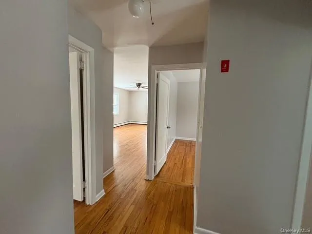 Hall with light wood-style flooring and baseboards Hall with light wood-style flooring and baseboards