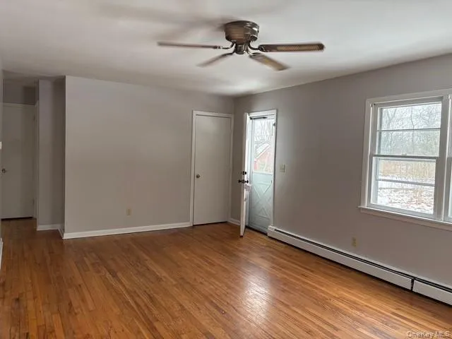 Spare room with baseboard heating, light wood-style floors, plenty of natural light, and a ceiling fan Spare room with baseboard heating, light wood-style floors, plenty of natural light, and a ceiling fan