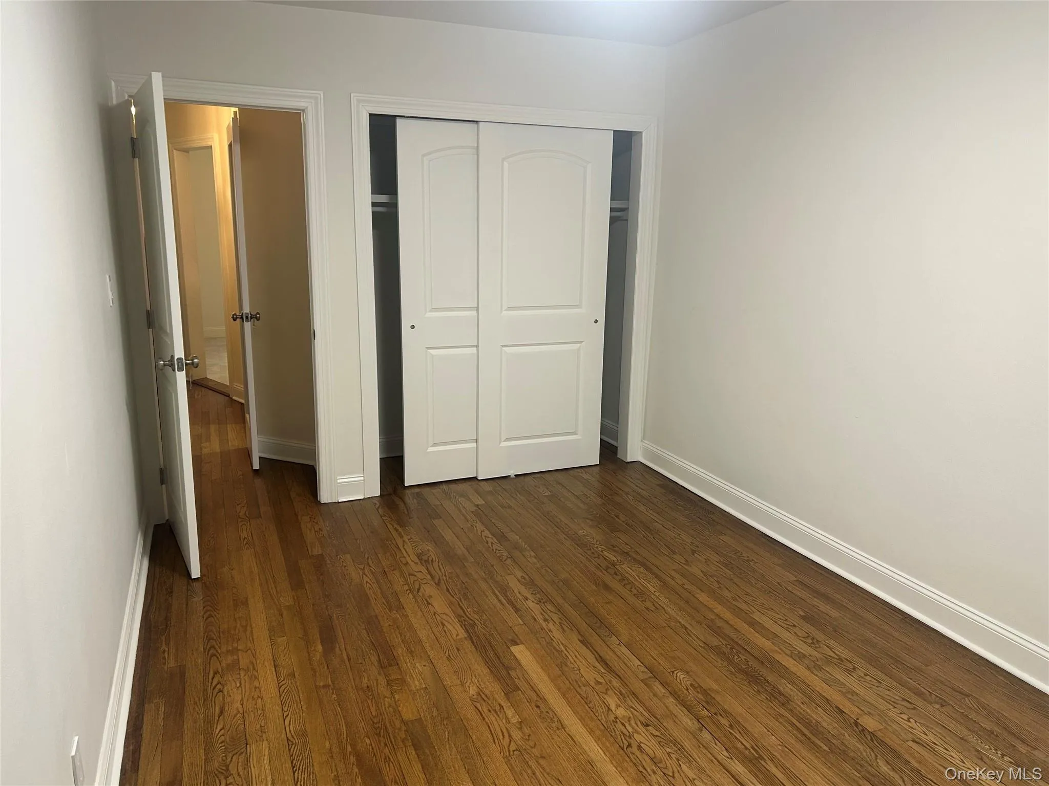 Unfurnished bedroom with dark wood-style flooring and a closet Unfurnished bedroom with dark wood-style flooring and a closet