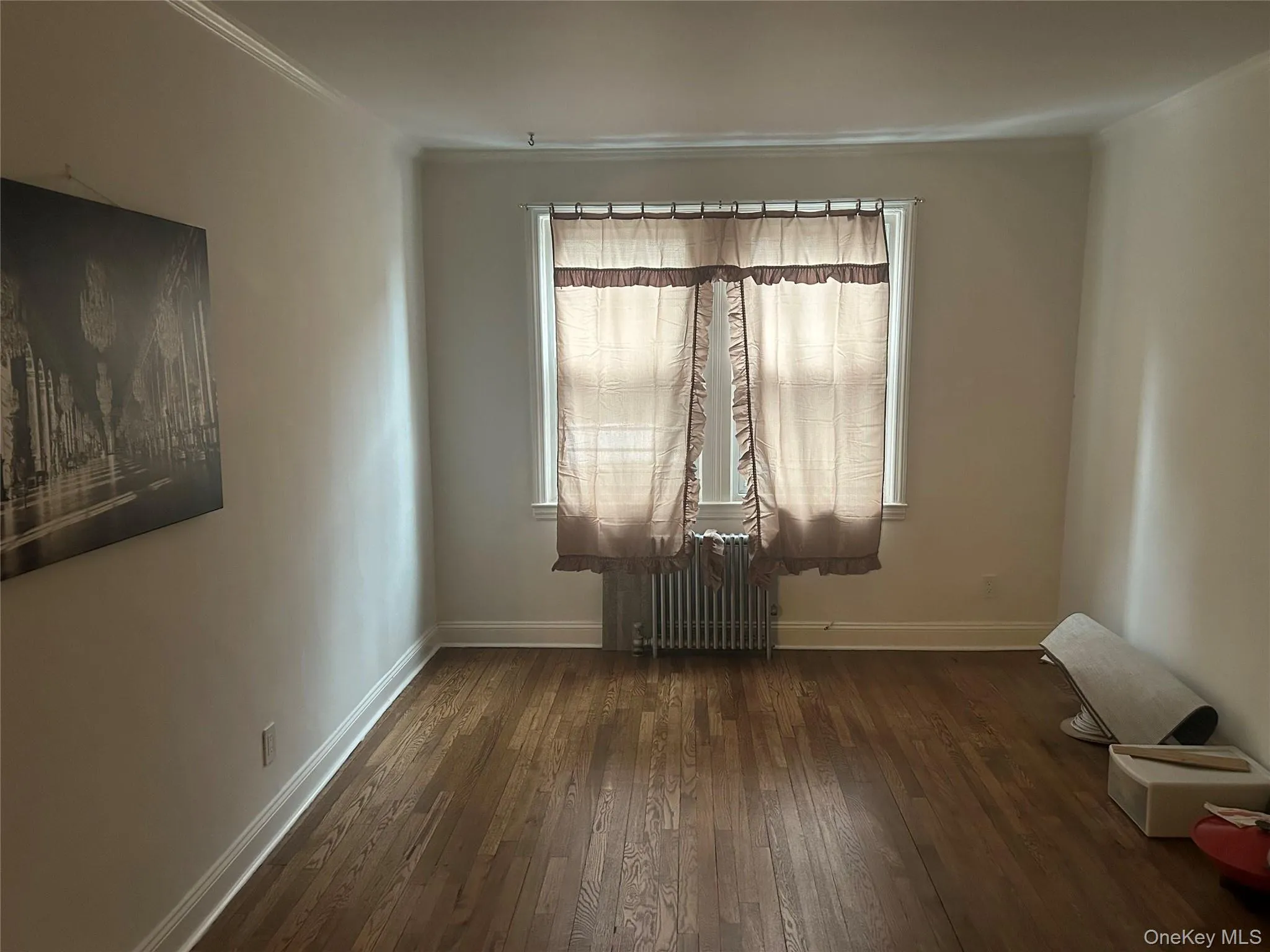 Unfurnished room with dark wood-type flooring, radiator heating unit, and crown molding Unfurnished room with dark wood-type flooring, radiator heating unit, and crown molding