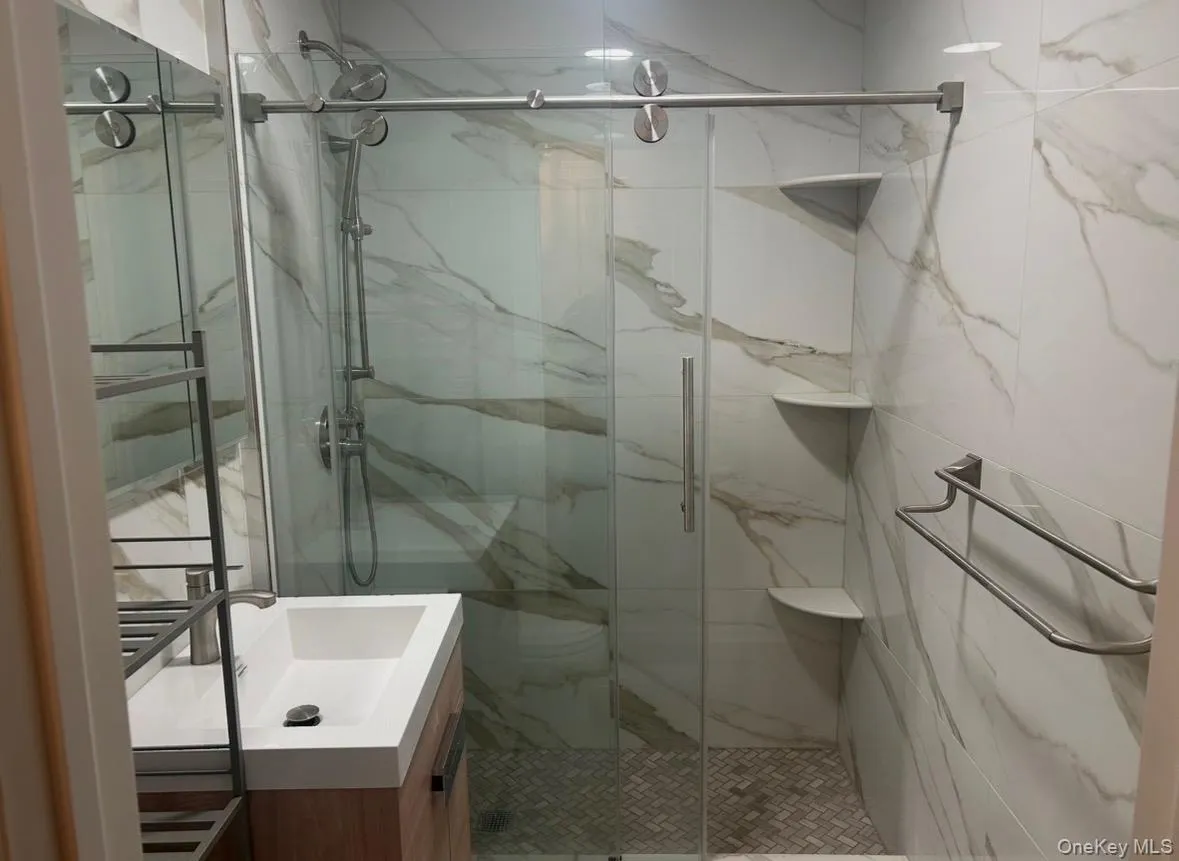 Full bathroom featuring vanity and a marble finish shower Full bathroom featuring vanity and a marble finish shower