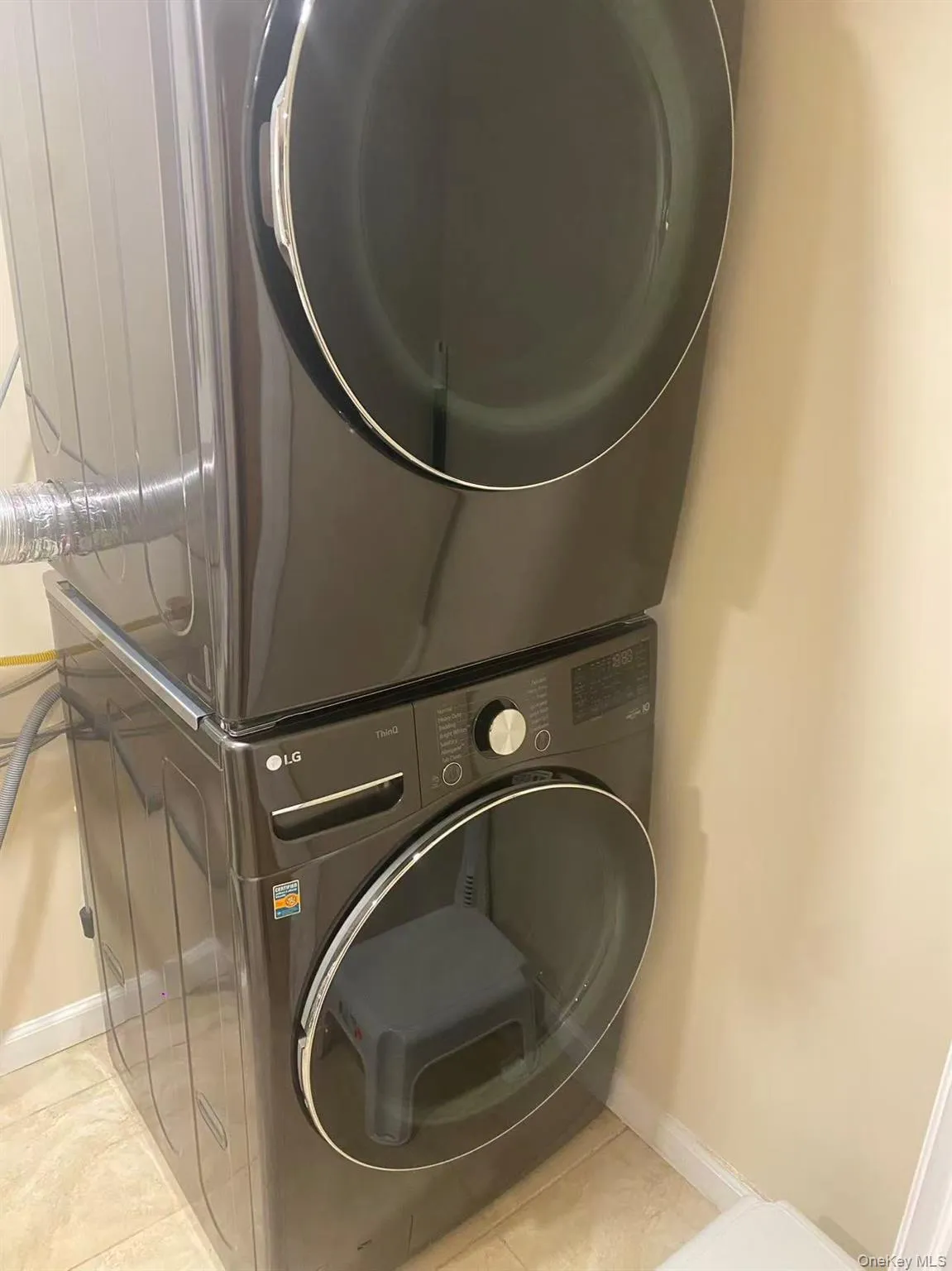 Washroom featuring estacked washer and dryer and tile patterned floors Washroom featuring estacked washer and dryer and tile patterned floors