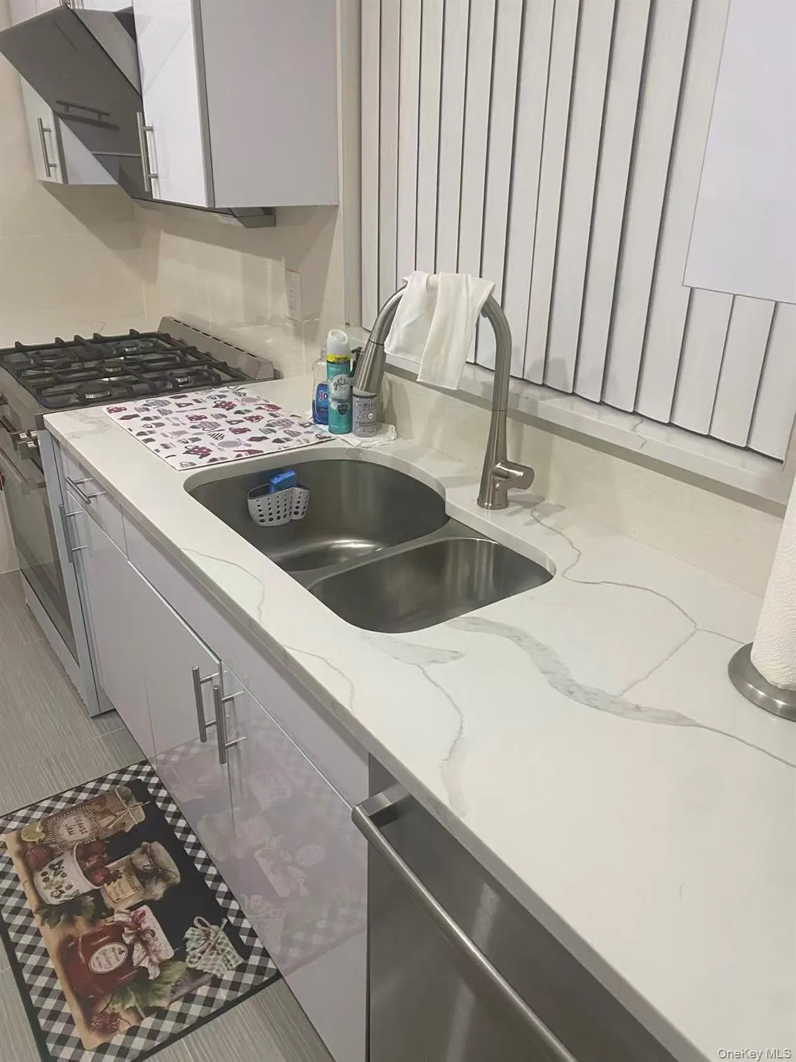 Kitchen with appliances with stainless steel finishes, light stone countertops, white cabinetry, gray cabinets, and exhaust hood Kitchen with appliances with stainless steel finishes, light stone countertops, white cabinetry, gray cabinets, and exhaust hood