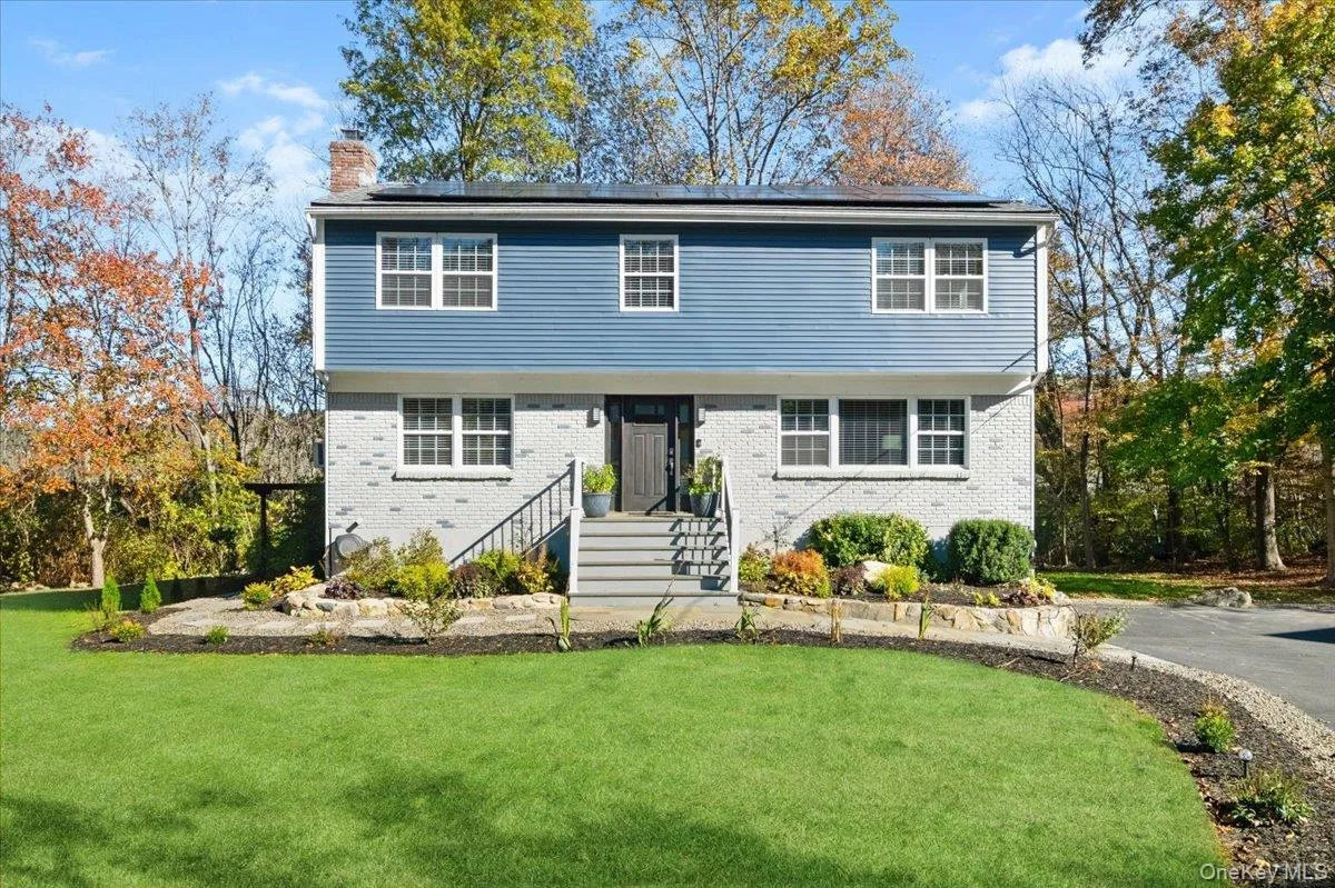 Colonial house with a front yard, a chimney, and solar panels Colonial house with a front yard, a chimney, and solar panels