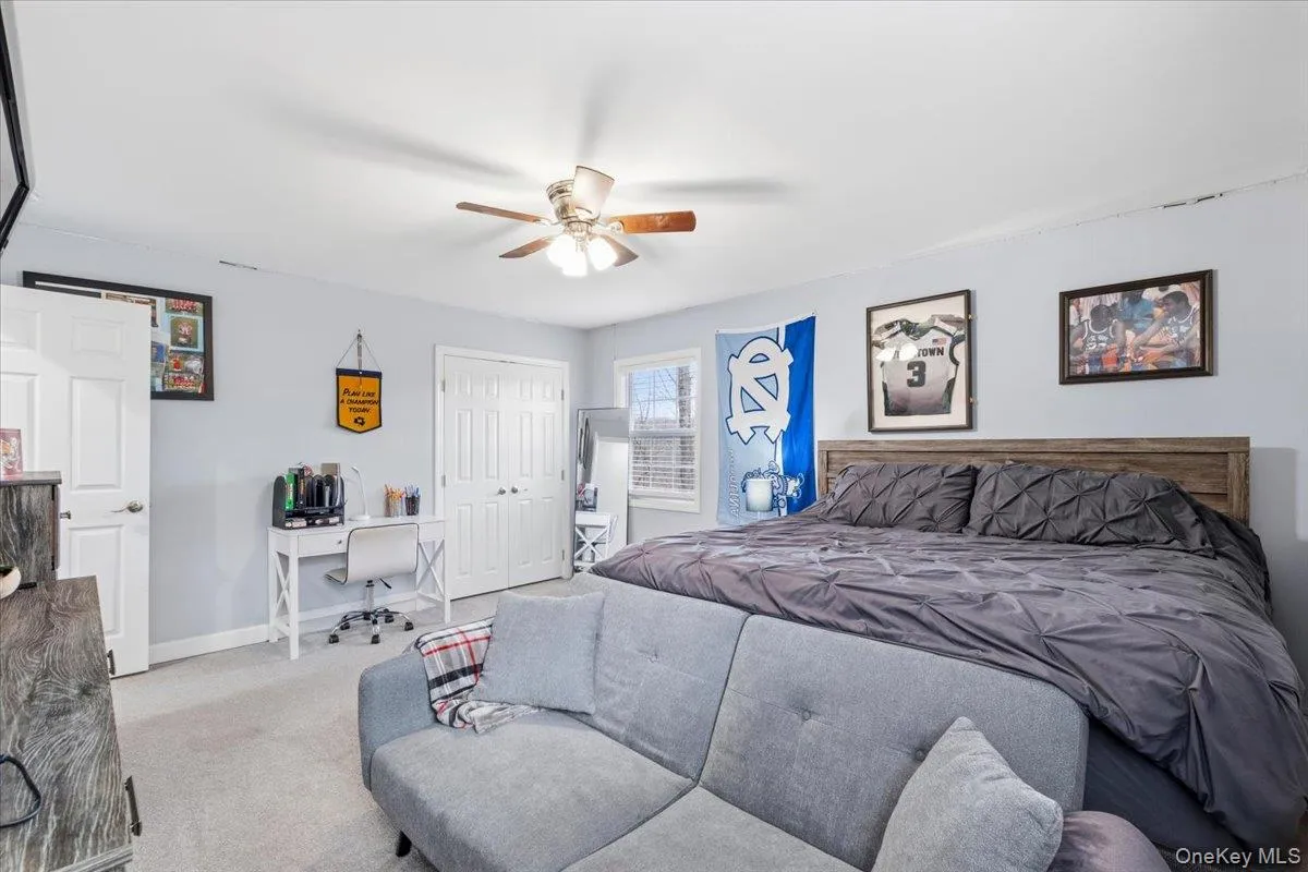 Carpeted bedroom featuring a desk, a closet, and a ceiling fan Carpeted bedroom featuring a desk, a closet, and a ceiling fan