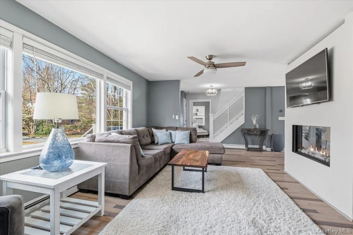 Living room with a glass covered fireplace, ceiling fan, and wood finished floors Living room with a glass covered fireplace, ceiling fan, and wood finished floors