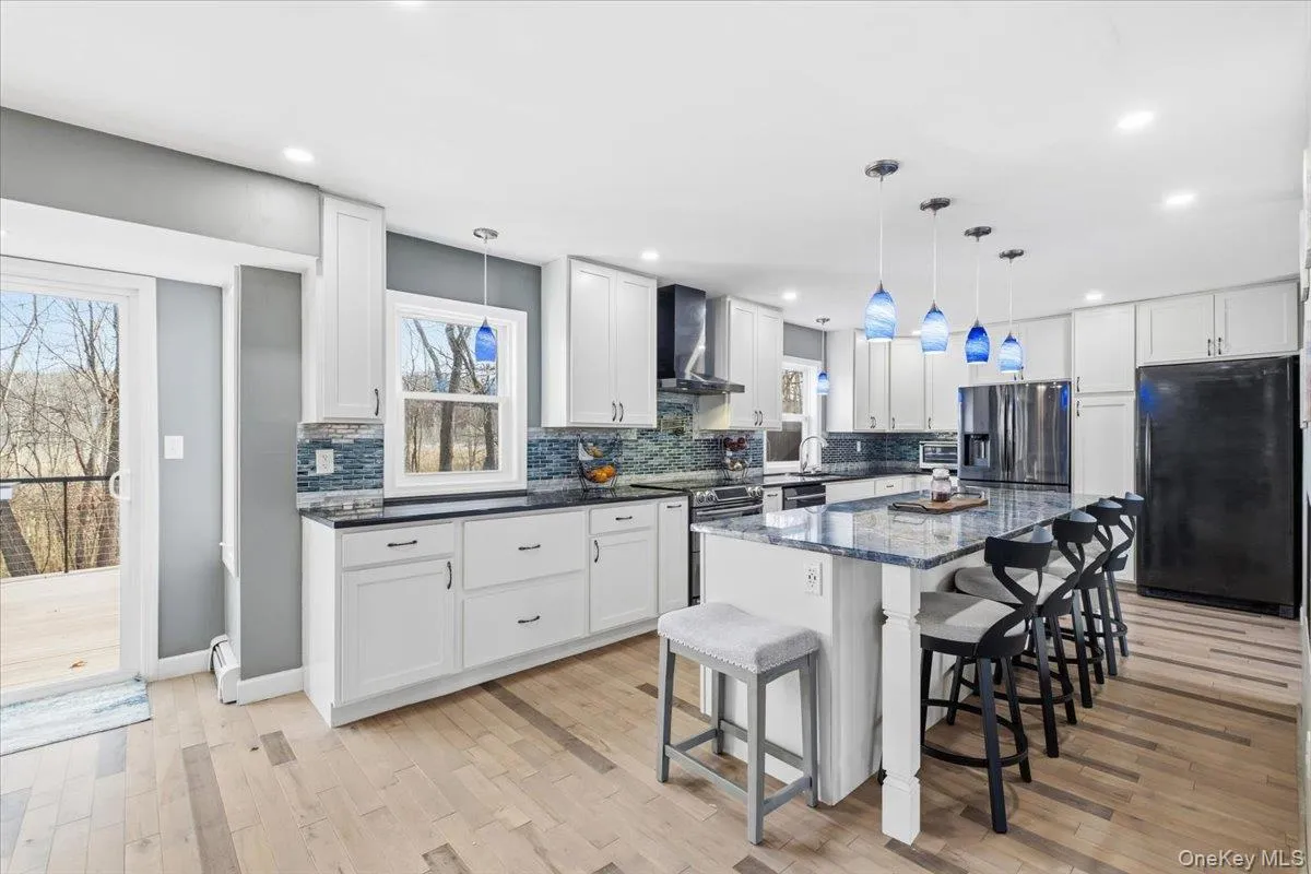 Kitchen featuring a breakfast bar, plenty of natural light, dark stone counters, freestanding refrigerator, and recessed lighting Kitchen featuring a breakfast bar, plenty of natural light, dark stone counters, freestanding refrigerator, and recessed lighting
