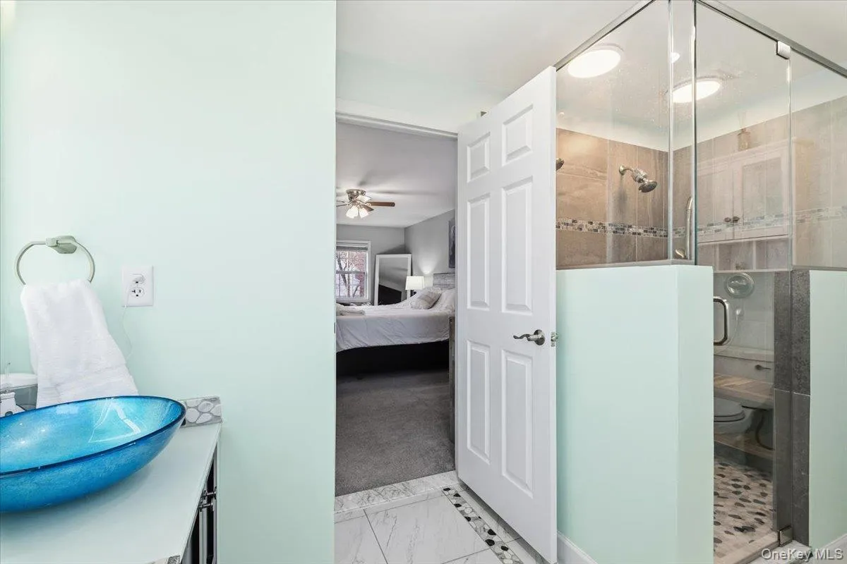 Ensuite bathroom featuring a stall shower, vanity, and a ceiling fan Ensuite bathroom featuring a stall shower, vanity, and a ceiling fan