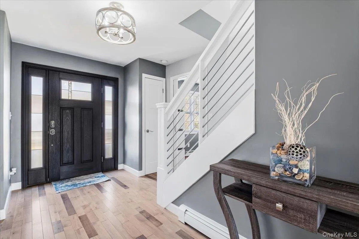 Foyer entrance with light wood-style floors, stairs, a baseboard radiator, and a chandelier Foyer entrance with light wood-style floors, stairs, a baseboard radiator, and a chandelier