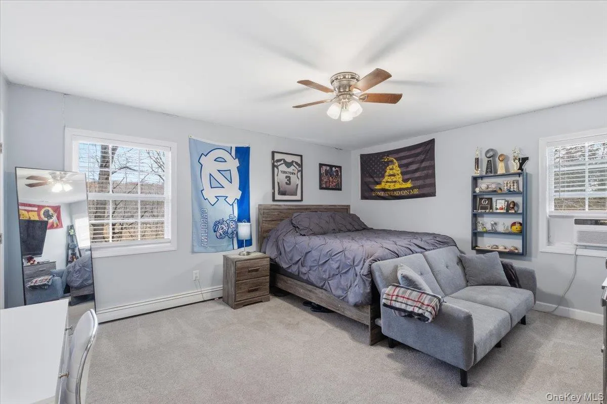 Bedroom featuring carpet, a baseboard heating unit, ceiling fan, and cooling unit Bedroom featuring carpet, a baseboard heating unit, ceiling fan, and cooling unit