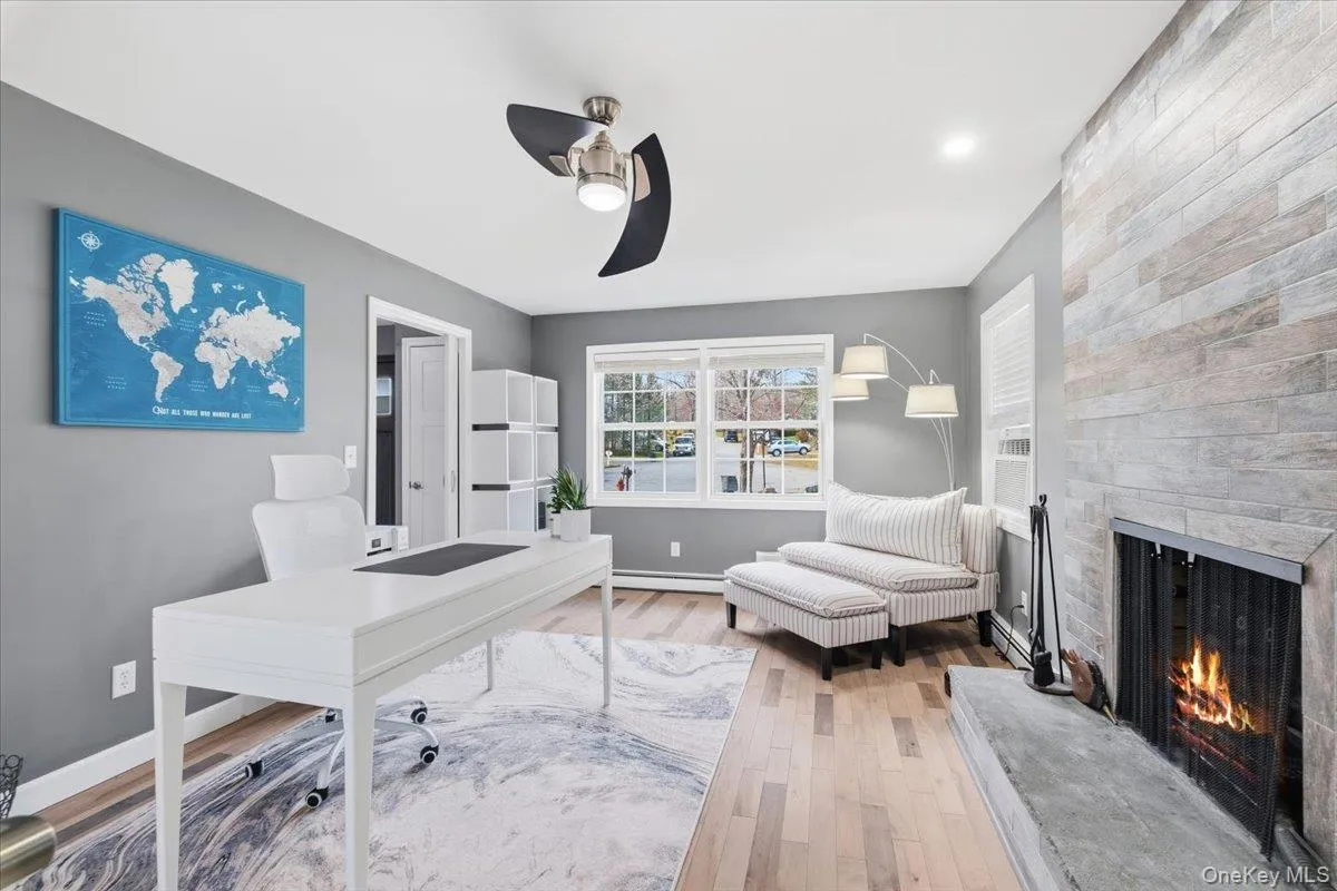 Office space featuring wood finished floors, a fireplace, a ceiling fan, a baseboard heating unit, and recessed lighting Office space featuring wood finished floors, a fireplace, a ceiling fan, a baseboard heating unit, and recessed lighting