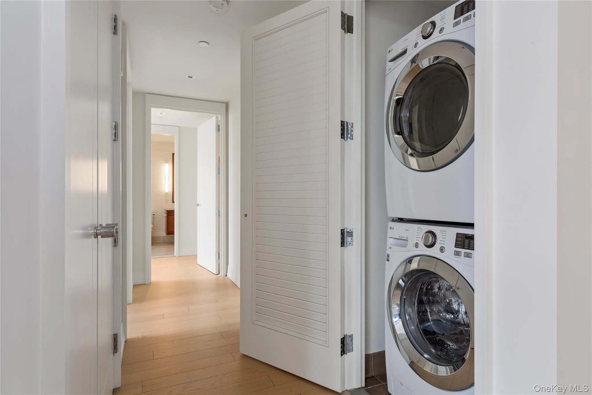 Washroom featuring light wood-style floors and stacked washer and clothes dryer Washroom featuring light wood-style floors and stacked washer and clothes dryer