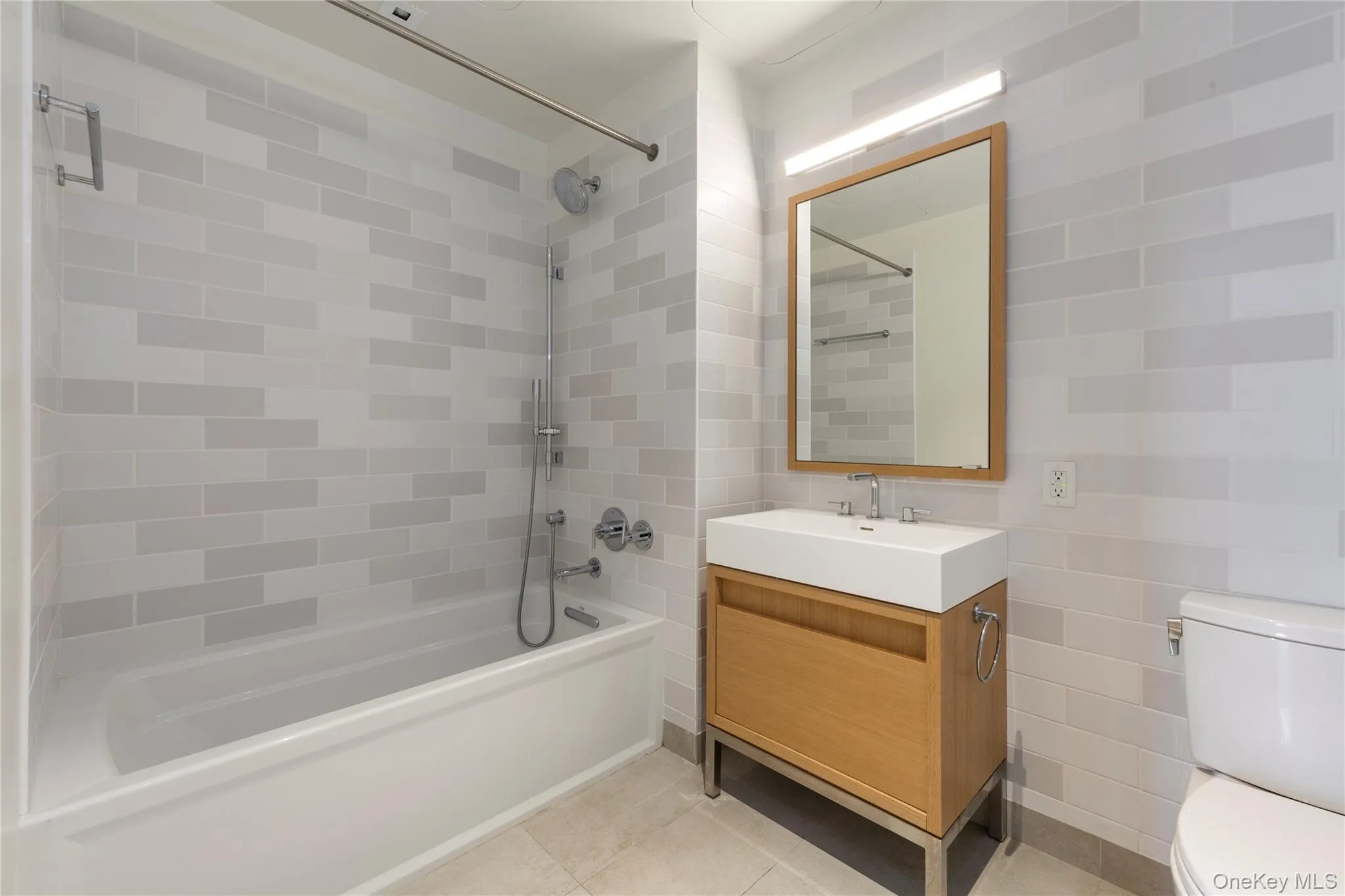 Bathroom featuring shower / washtub combination, vanity, tile walls, and light tile patterned floors Bathroom featuring shower / washtub combination, vanity, tile walls, and light tile patterned floors