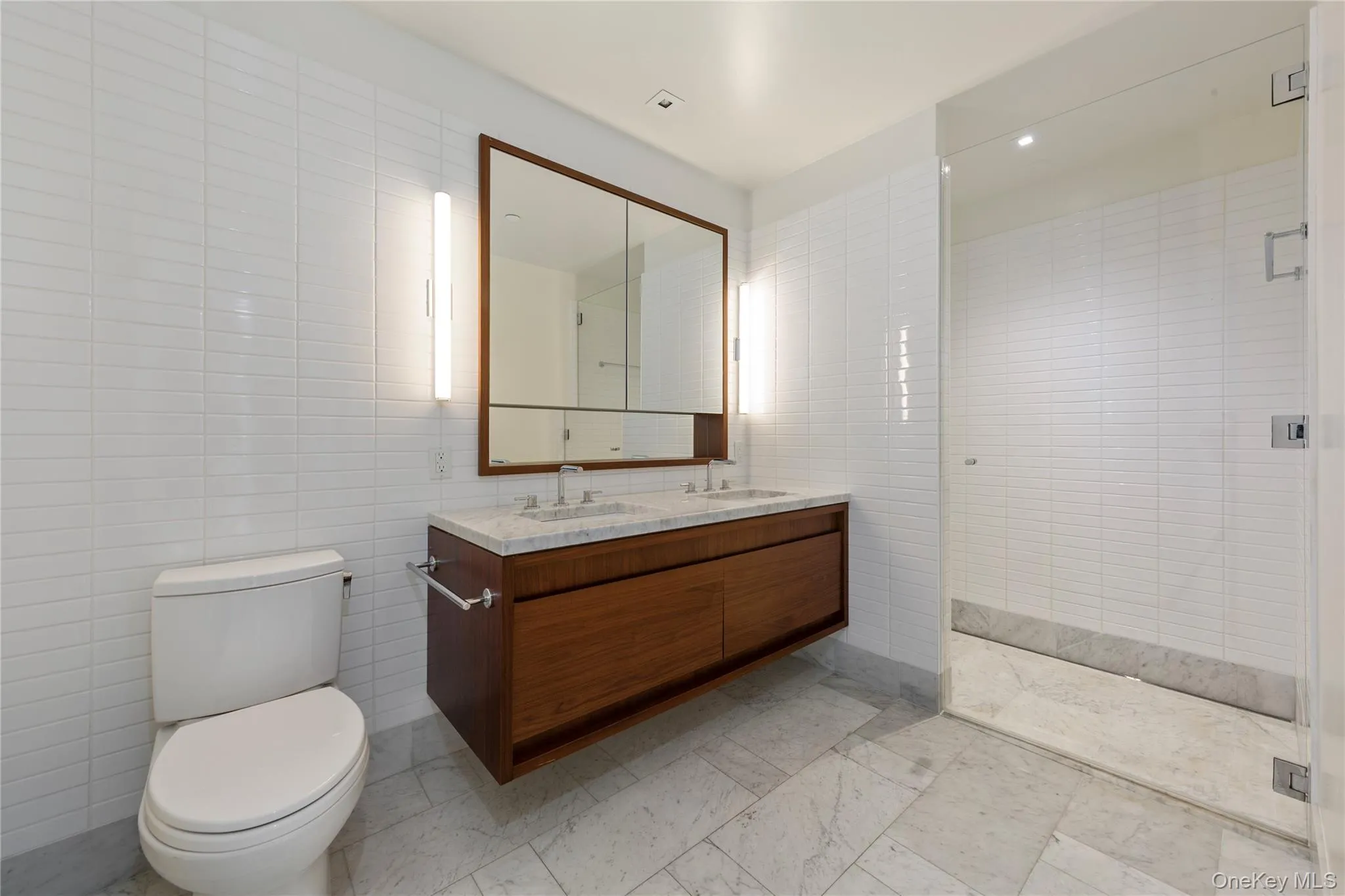 Bathroom featuring tile walls, double vanity, and a stall shower Bathroom featuring tile walls, double vanity, and a stall shower