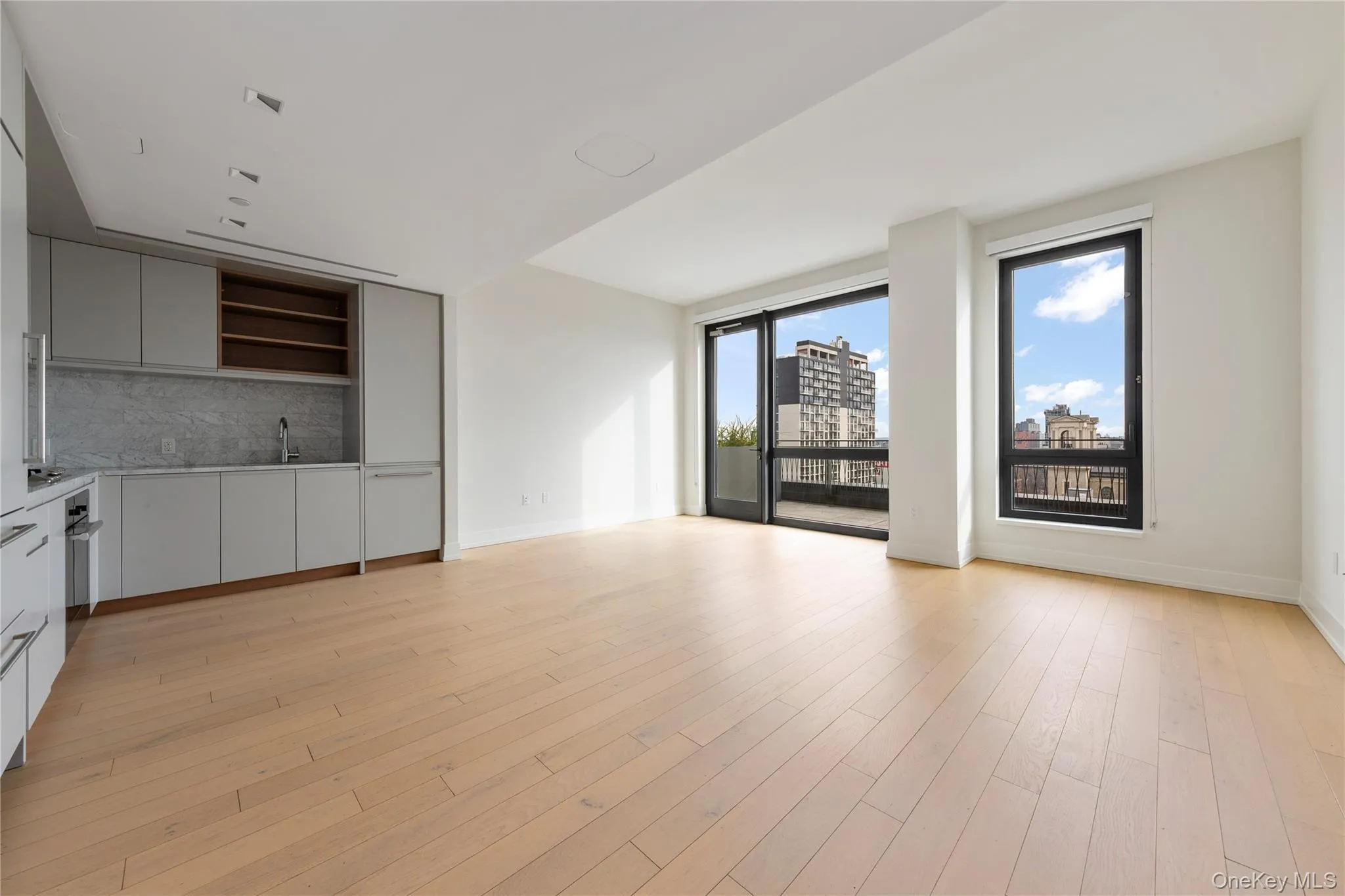 Unfurnished living room featuring light wood-style floors, a view of city, and wet bar Unfurnished living room featuring light wood-style floors, a view of city, and wet bar