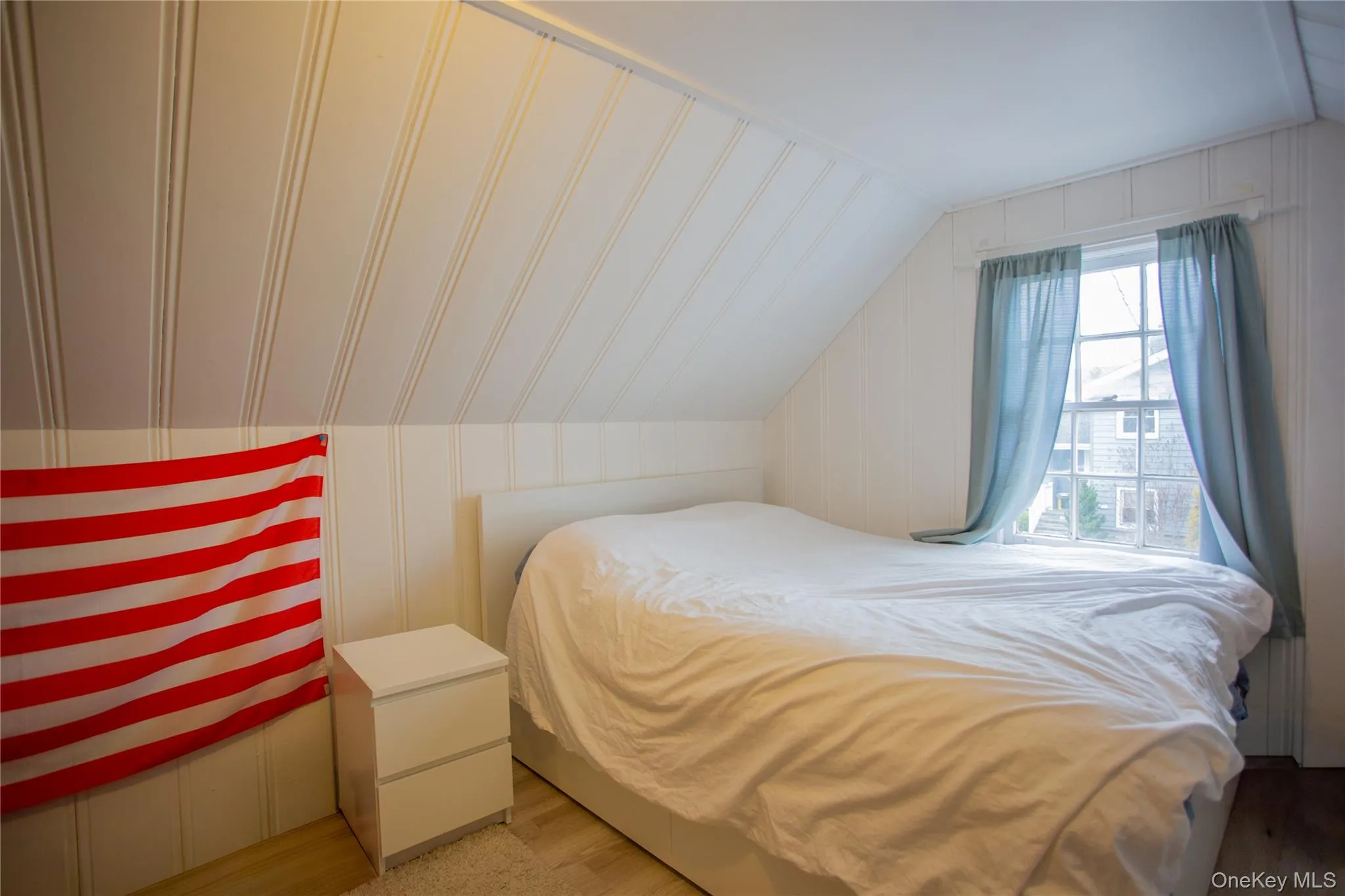 Bedroom featuring vaulted ceiling and a decorative wall Bedroom featuring vaulted ceiling and a decorative wall