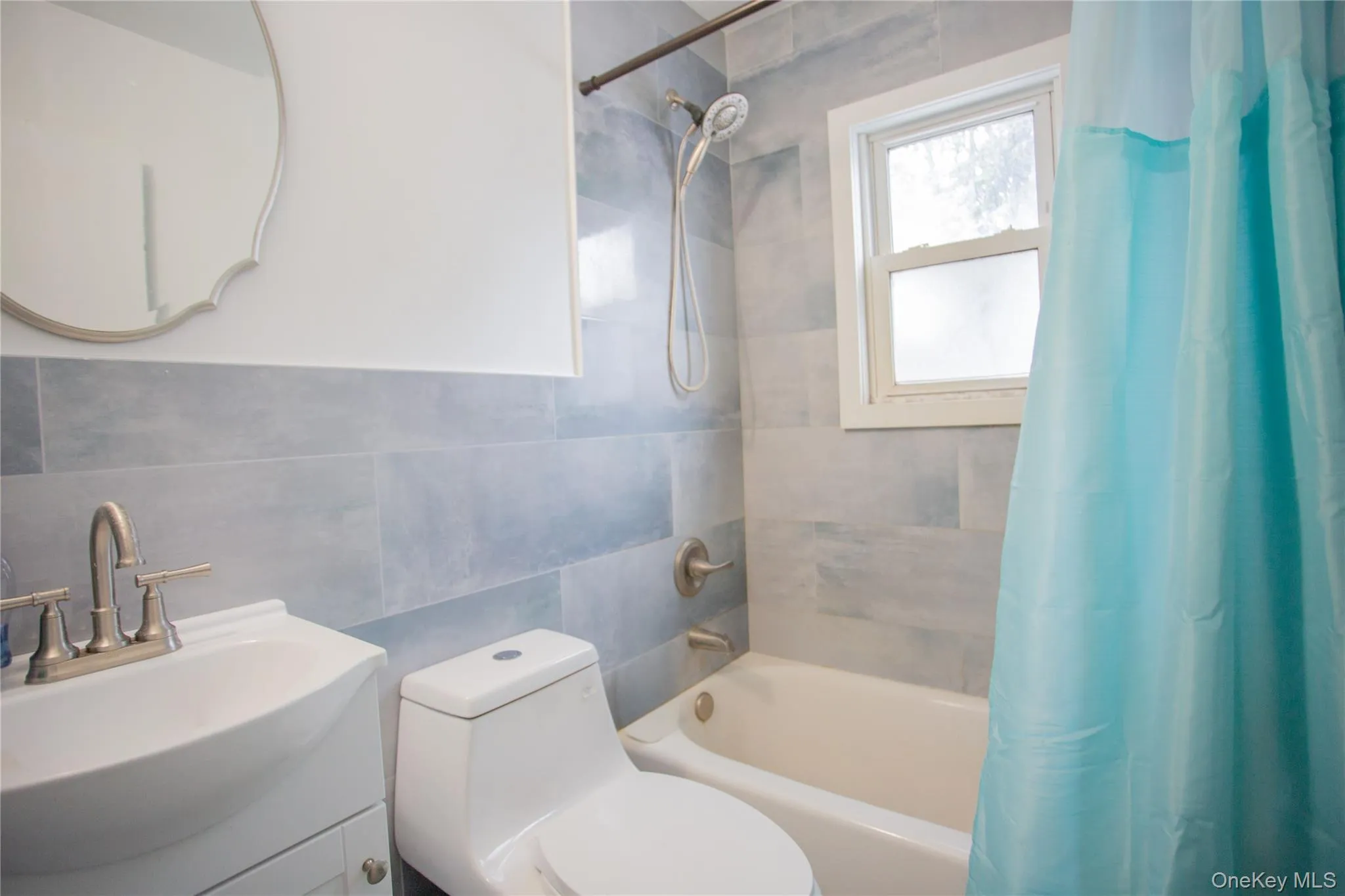 Full bath featuring shower / tub combo with curtain, vanity, and tile walls Full bath featuring shower / tub combo with curtain, vanity, and tile walls