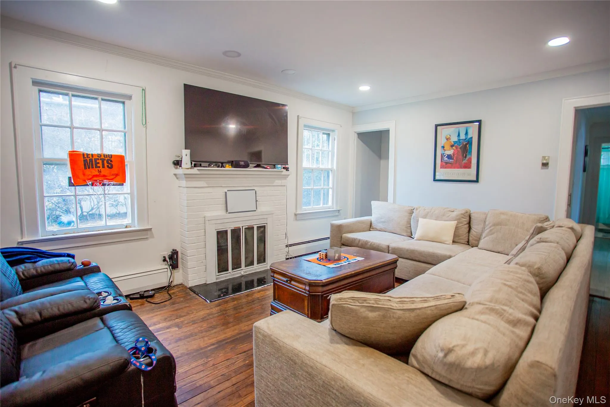 Living area with wood-type flooring, crown molding, a fireplace, baseboard heating, and recessed lighting Living area with wood-type flooring, crown molding, a fireplace, baseboard heating, and recessed lighting